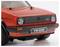 Egy piros vintage VW Golf GTI modellautó elölnézete, jellegzetes kerek fényszórókkal és klasszikus hűtőráccsal, fehér háttér előtt.