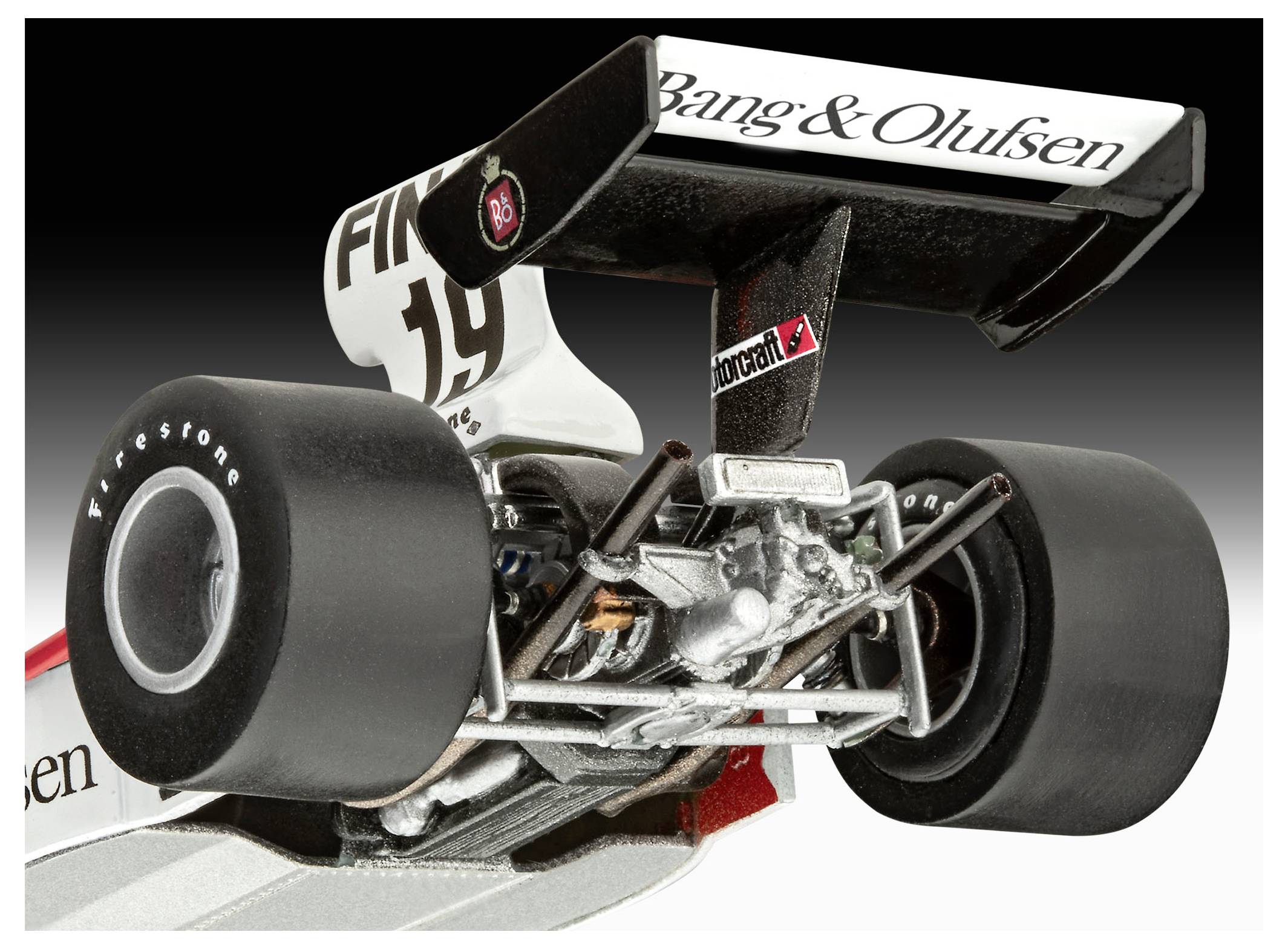 Egy Formula 1-es versenyautó részletes modelljének hátsó nézete, amelyen elegáns fekete kerekek, egy aerodinamikus szárny Bang & Olufsen logóval és aprólékosan kidolgozott motorrészletek láthatók.