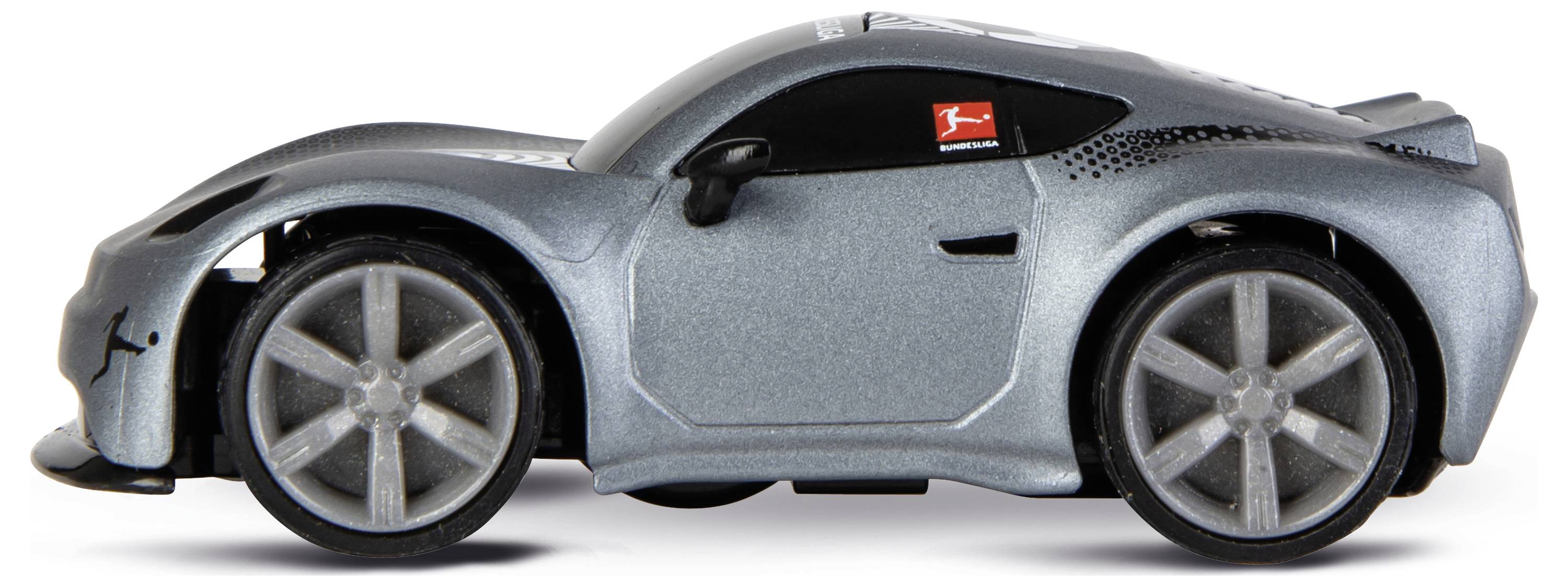 Egy ezüst játék sportautó nagy kerekekkel és áramvonalas formatervezéssel, oldalról nézve fehér háttér előtt.