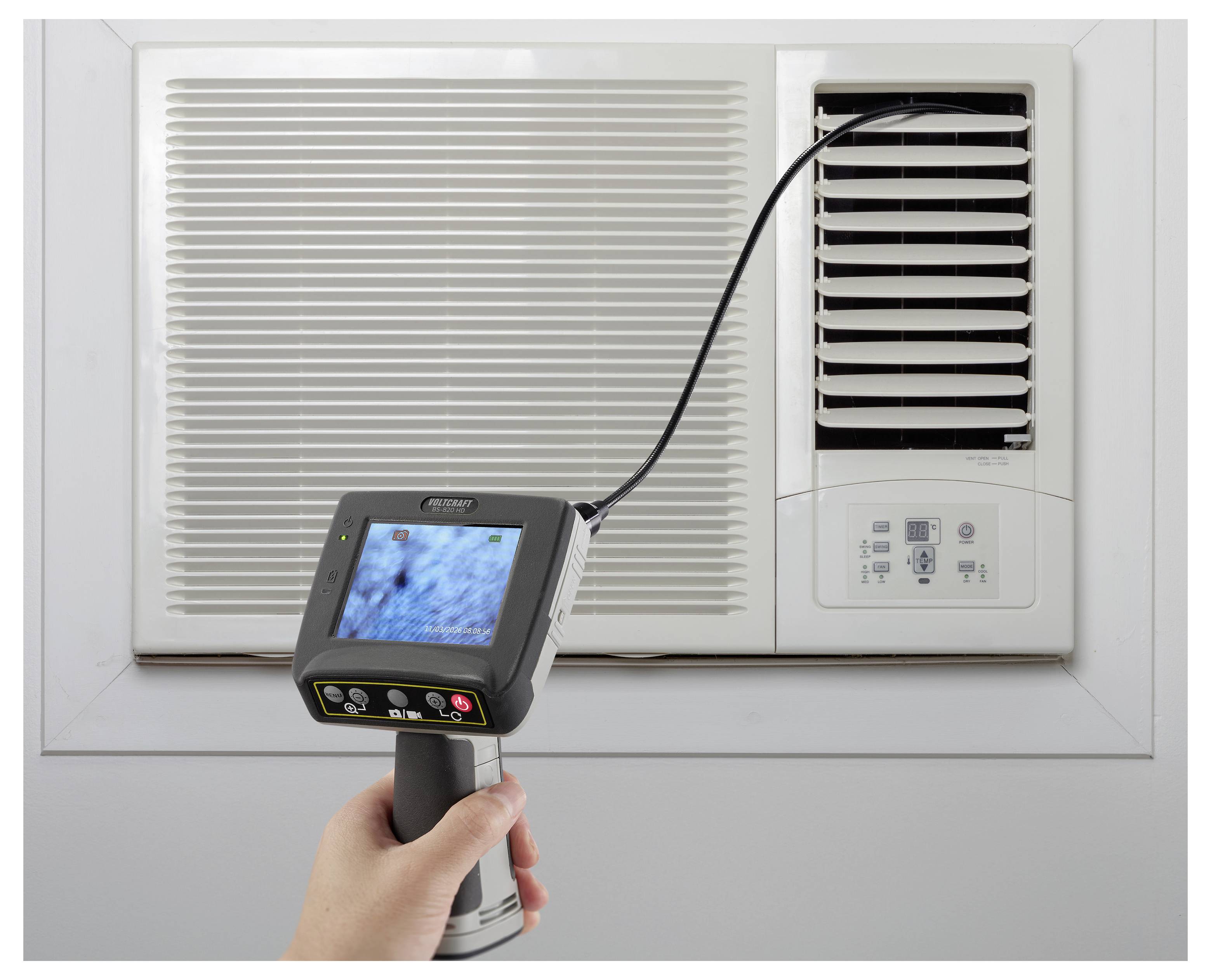 Kézi inspekciós kamera, amely egy légkondicionáló szellőzőnyílást vizsgál fel rugalmas kábellel, valószínűleg HVAC karbantartáshoz vagy diagnosztikához.