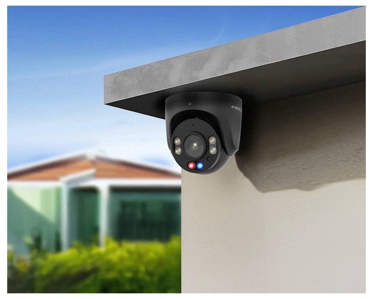 Egy fekete biztonsági kamera van felszerelve egy kültéri falon, amely egy külvárosi területet figyel, elmosódott házakkal és növényzettel a háttérben.