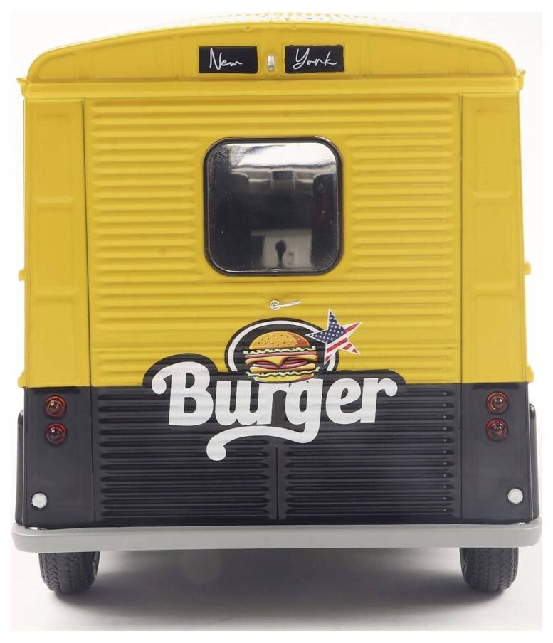 Egy sárga és fekete ételbusz, amelyen a 'Burger' felirat és egy hamburger illusztráció látható a hátsó részén. A kisméretű tábla felette 'New York' felirattal van ellátva.