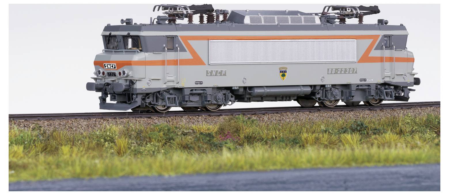 Egy kiállított modellvasút mozdony, szürke és narancssárga dizájnnal, aprólékos részletekkel, vasúti síneken elhelyezve.