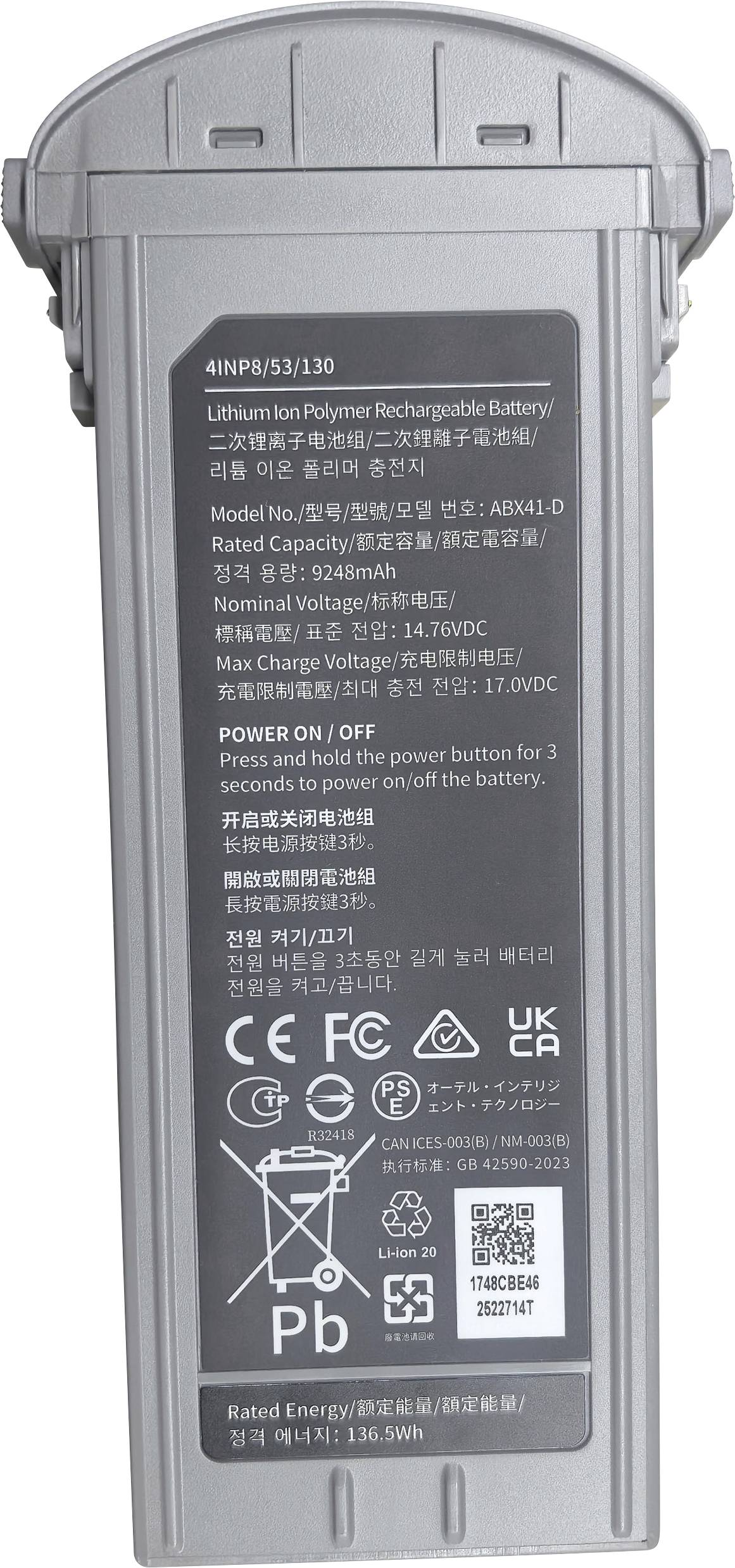 Egy téglalap alakú lítium-ion polimer újratölthető akkumulátor, amely műszaki specifikációkat, biztonsági ikonokat és a tápgomb használatára vonatkozó utasításokat tartalmazó címkékkel van ellátva.