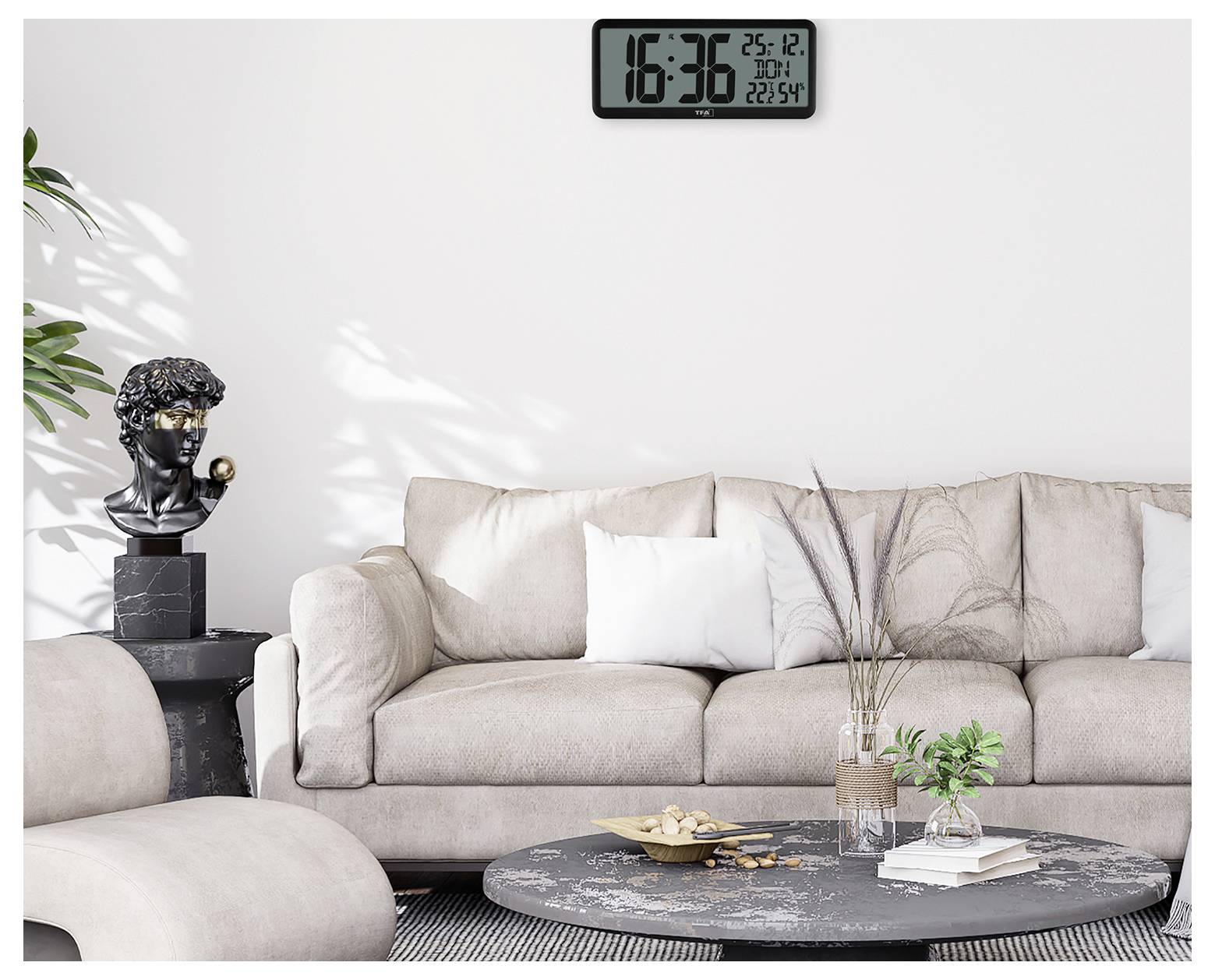 Egy modern nappali egy bézs színű kanapéval, egy fekete szoborral egy kisasztalon, és egy digitális órával, amely '16:36 25.12'-t mutat.