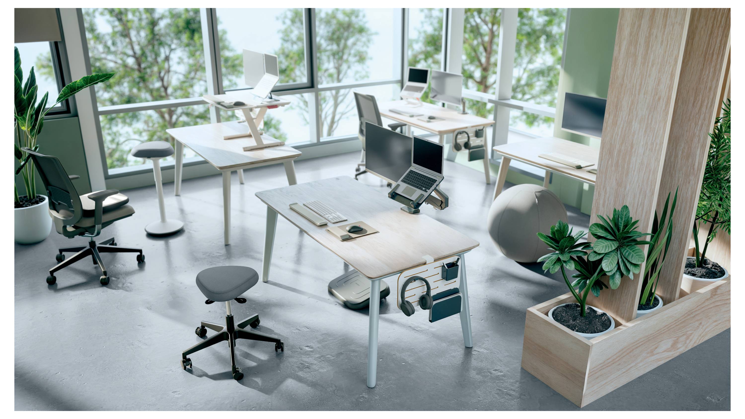 Modern irodai tér több állítható magasságú íróasztallal, számítógépekkel, ergonomikus székekkel, növényekkel és nagy ablakokkal, amelyekből zöld kilátás nyílik.