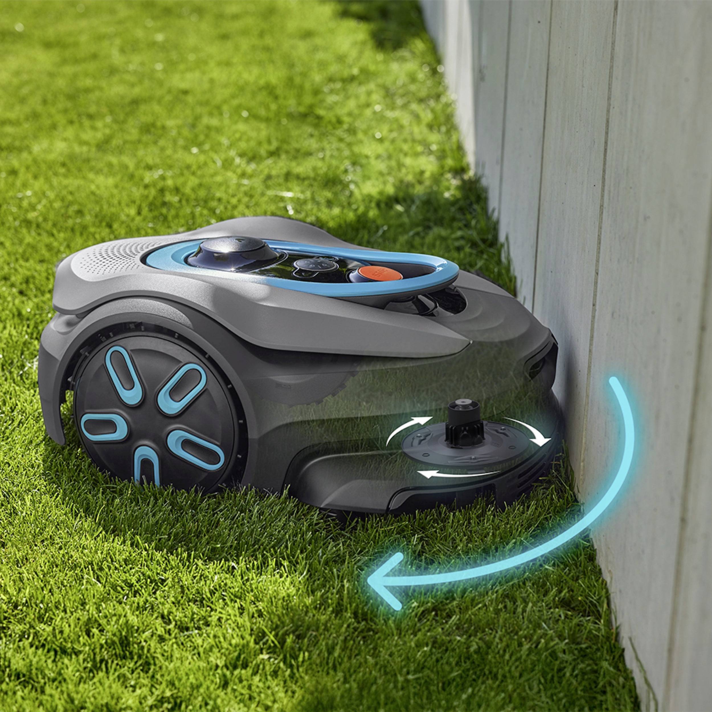 Egy neonkék részletekkel ellátott robotfűnyíró fűvet vág egy fa kerítés mentén, bemutatva az automatizált kertgondozást.