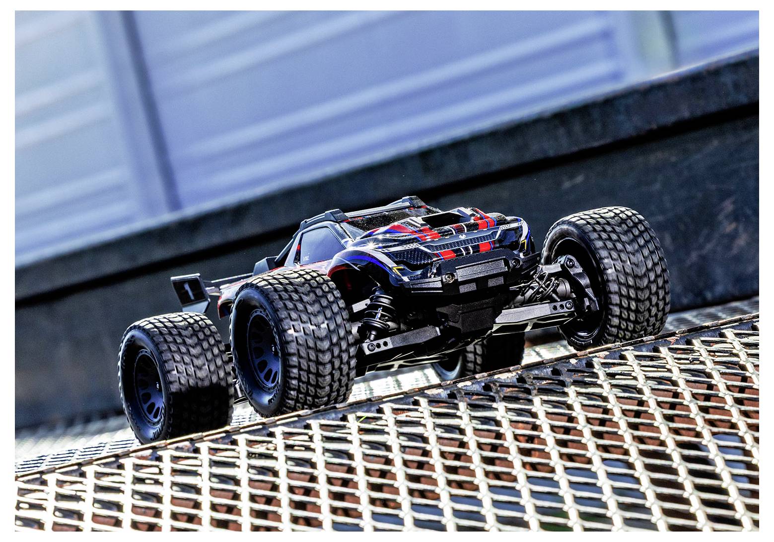 Egy távirányítós autó egy fémrácsozatú rámpán, amelyen hangsúlyosan jelenik meg a jármű robusztus felépítése és terepjáró képessége.