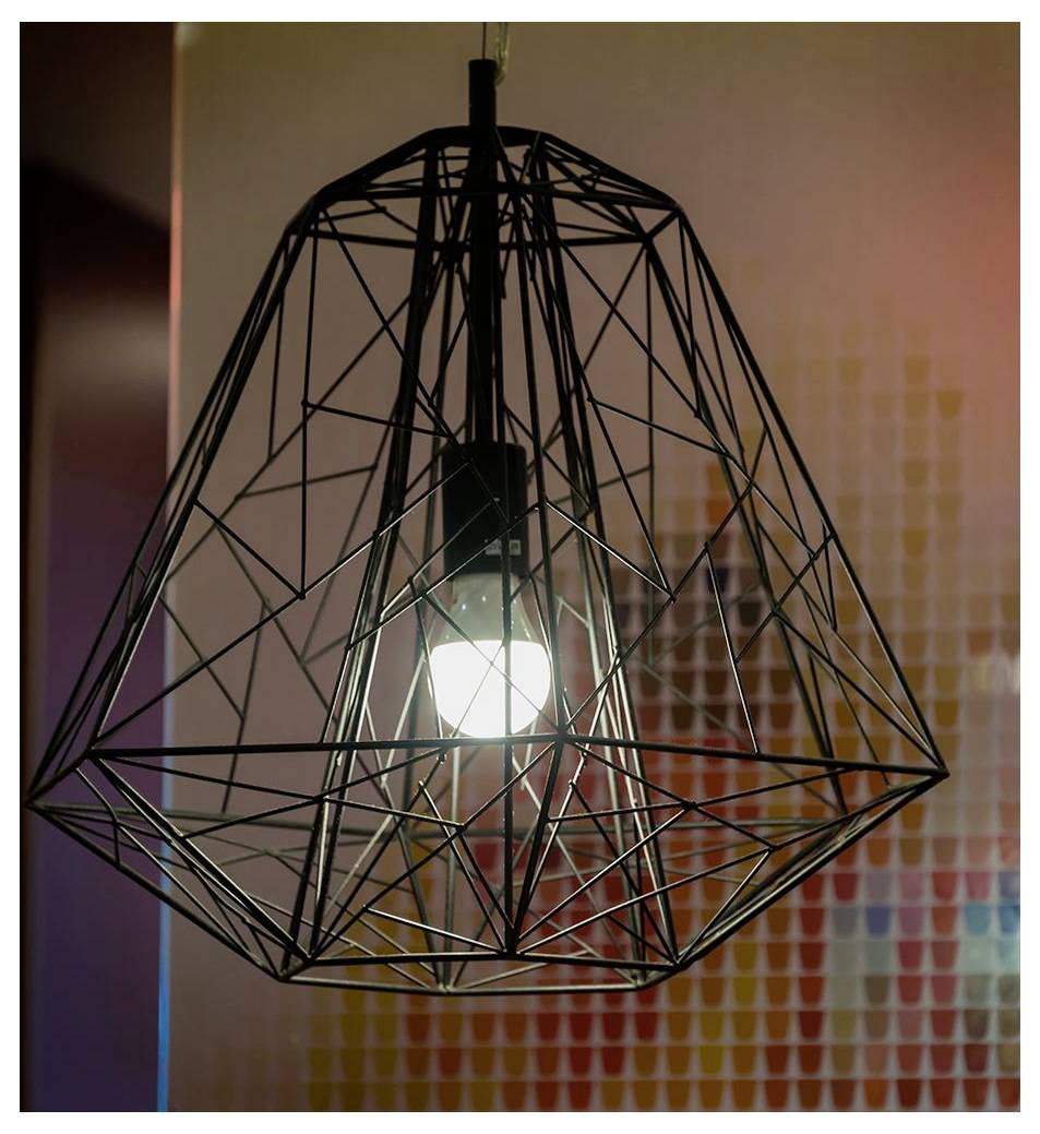 Egy modern, geometriai drótváz-dizájnú függőlámpa ég lámpabúrájával egy elmosódott, színes mozaikminták által keretezett háttér előtt függ.