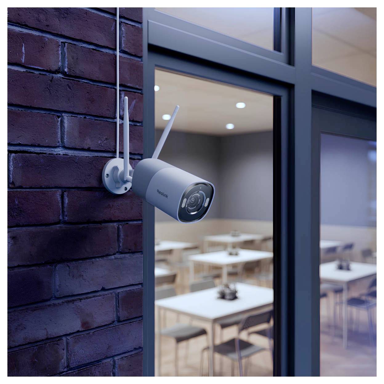 Biztonsági kamera egy téglafal előtt, egy ablak közelében, egy beltéri étkezőhelyiség fölött, amelyben asztalok és székek láthatók.