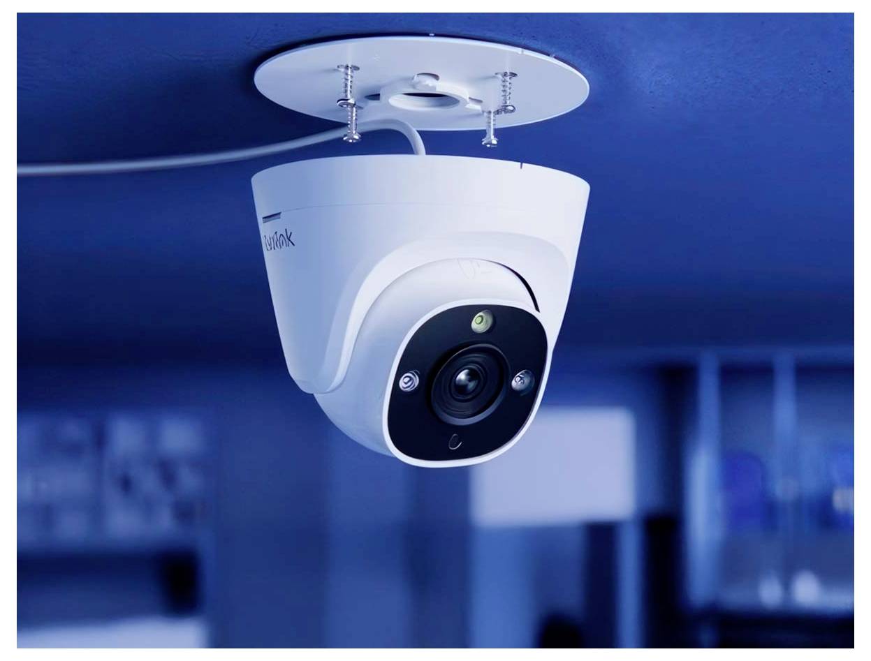 Egy fehér burkolatú, mennyezetre szerelt biztonsági kamera helyezkedik el egy modern beltéri környezetben, videófelvételt rögzítve felügyeleti célból.