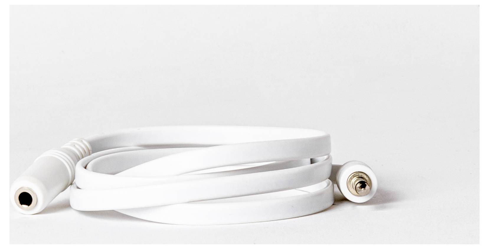 Egy tekeredő fehér audió kábel, amelynek egyik végén női jack csatlakozó, a másik végén férfi dugó van, fehér felületen elhelyezve.