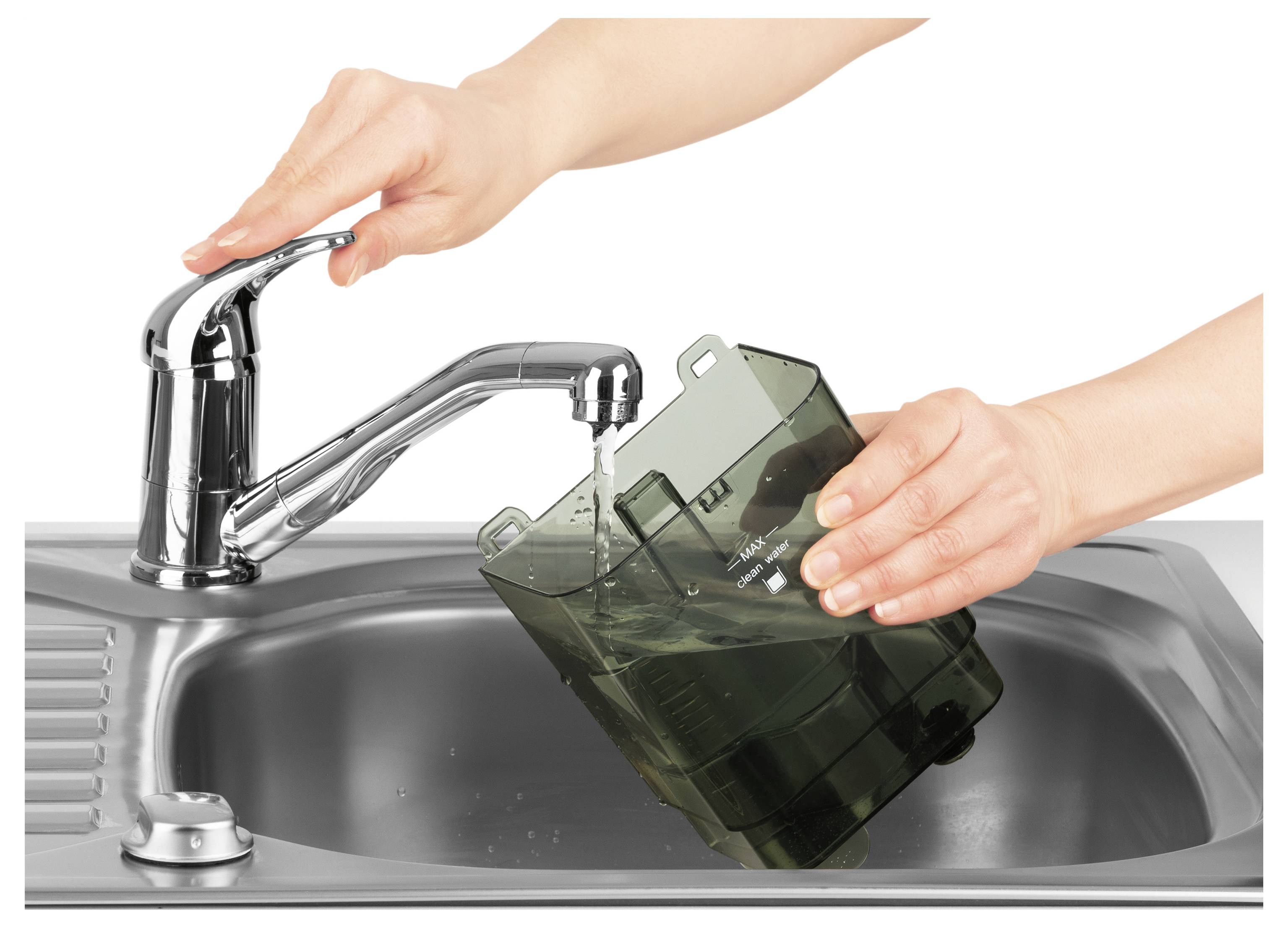 Egy személy átlátszó sötét tárolót tölt meg vízzel a konyhai csapból, felhasználásra készülve, egy fémes mosogató fölött.