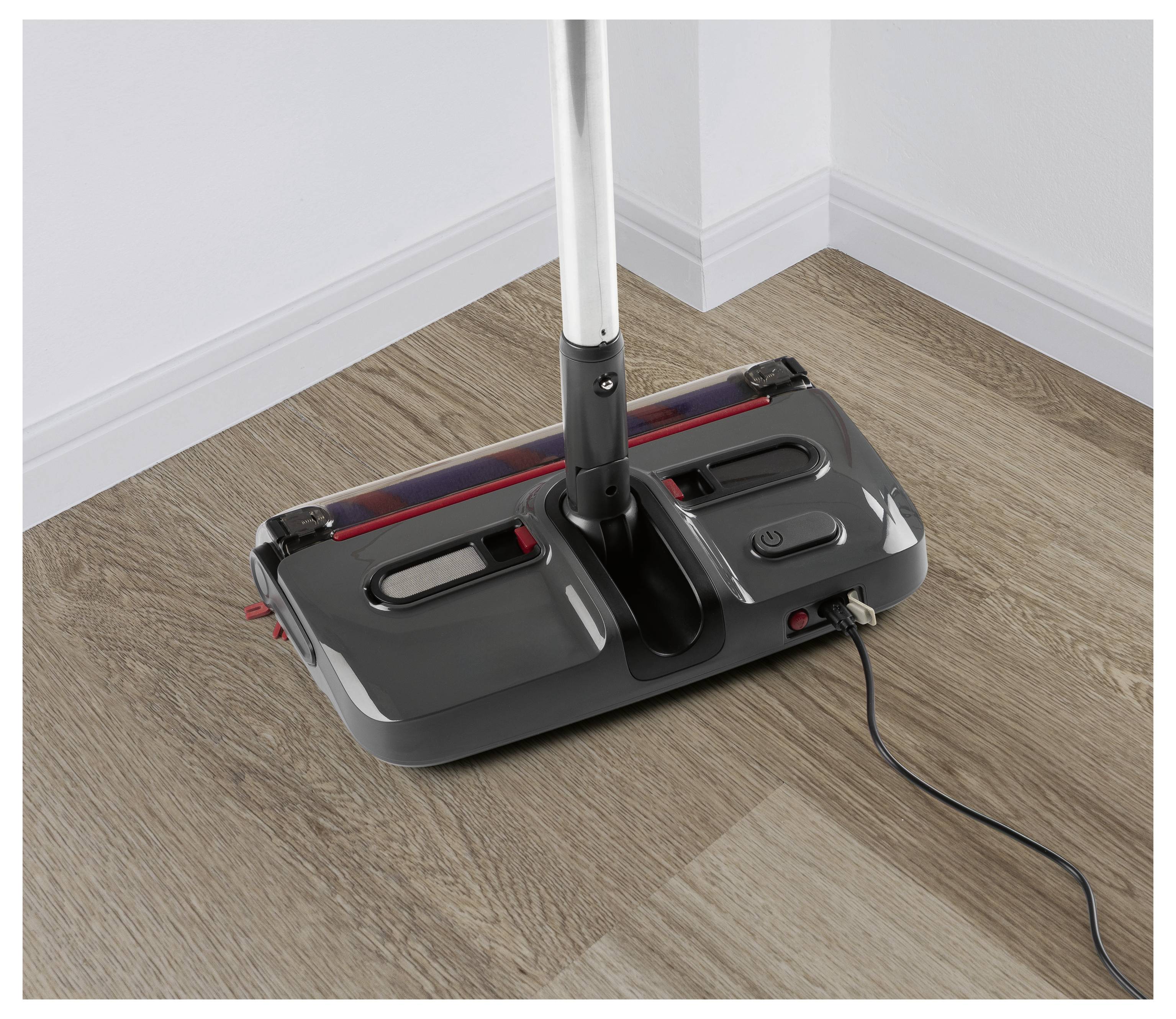 Elektromos padlósöprő egy fapadlón, bedugva és használatra kész.