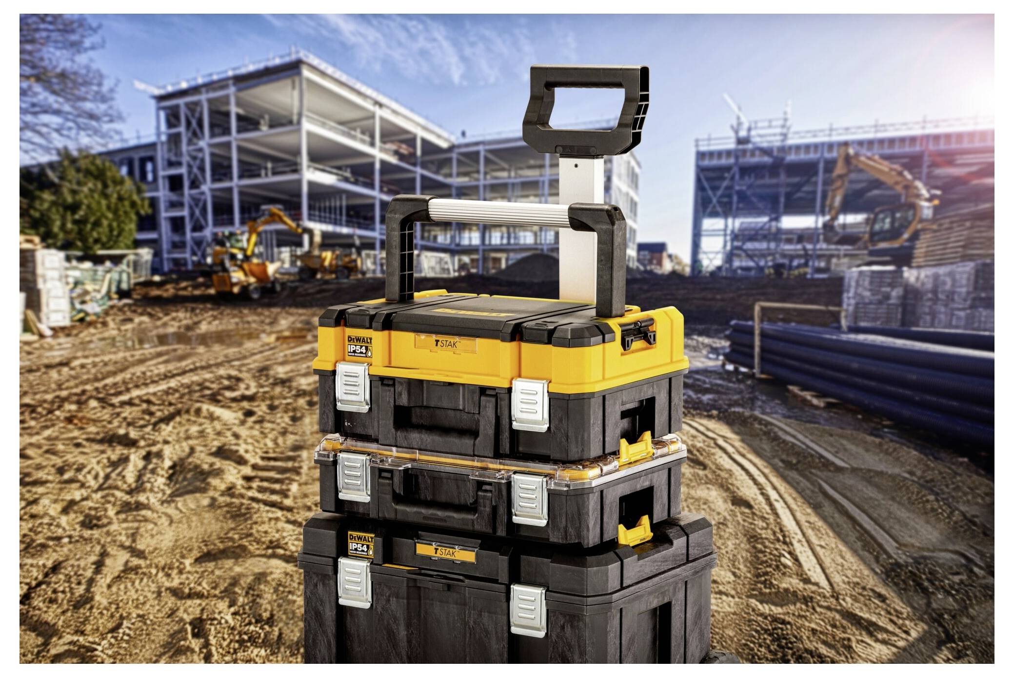 Fekete és sárga szerszámosládák fogantyúkkal a Construction site-nak előterében. Acélszerkezetek és gépek a háttérben.