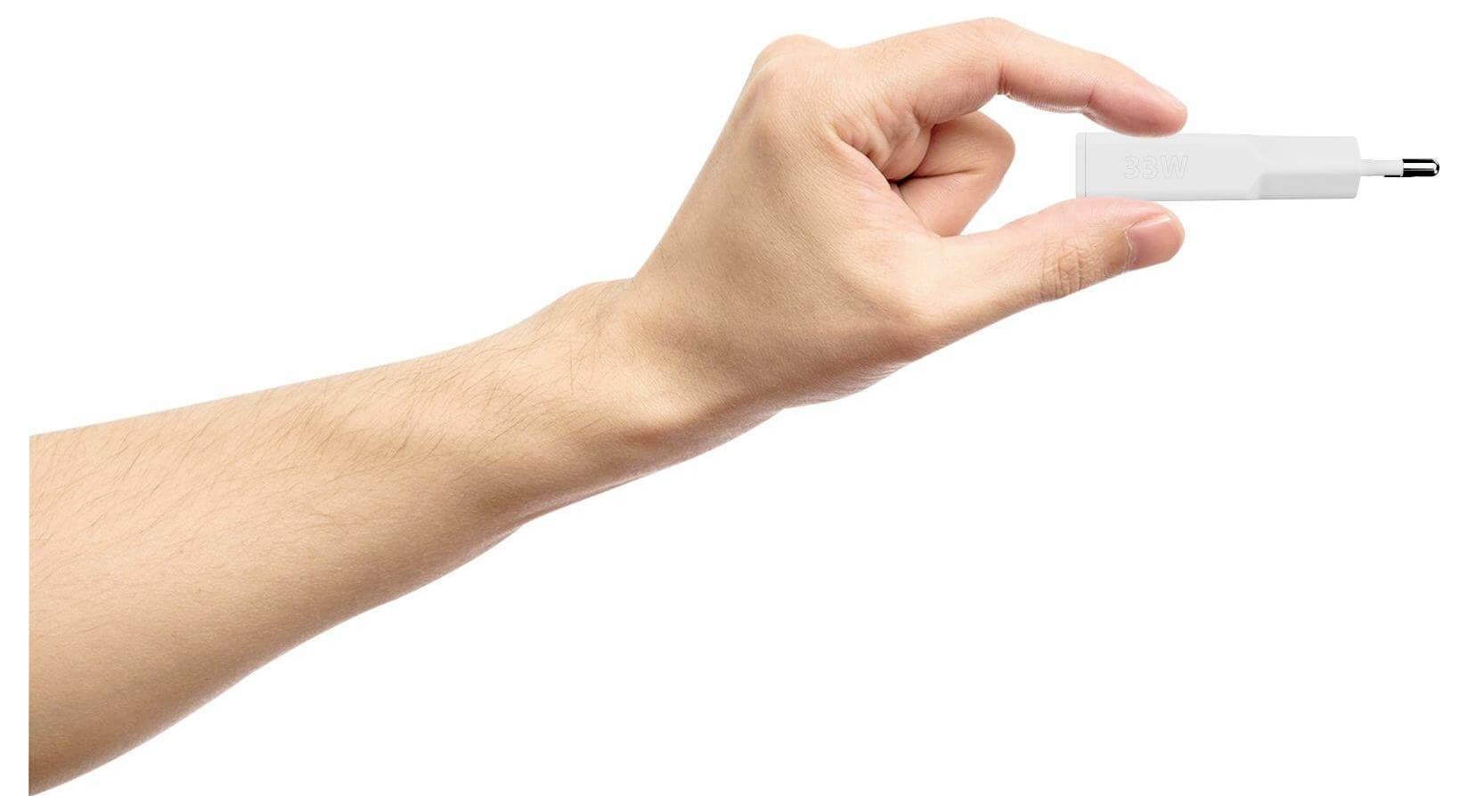 Egy kéz egy kis USB-meghajtót tart hüvelyk- és mutatóujja között fehér háttér előtt.