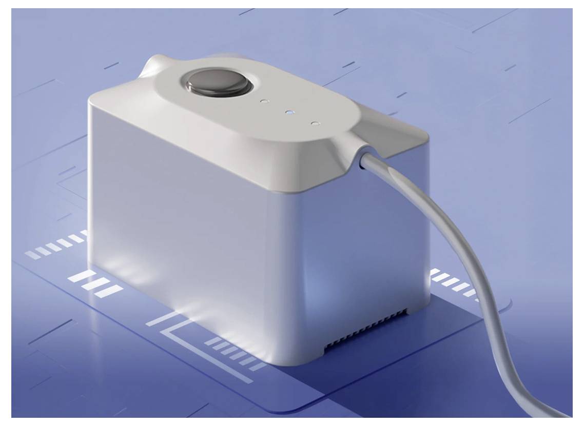 Egy fehér téglalap alakú elektronikus eszköz, amelyen egy kör alakú gomb található a tetején, egy kábellel csatlakoztatva egy kék felületre, amely digitális mintákat tartalmaz.