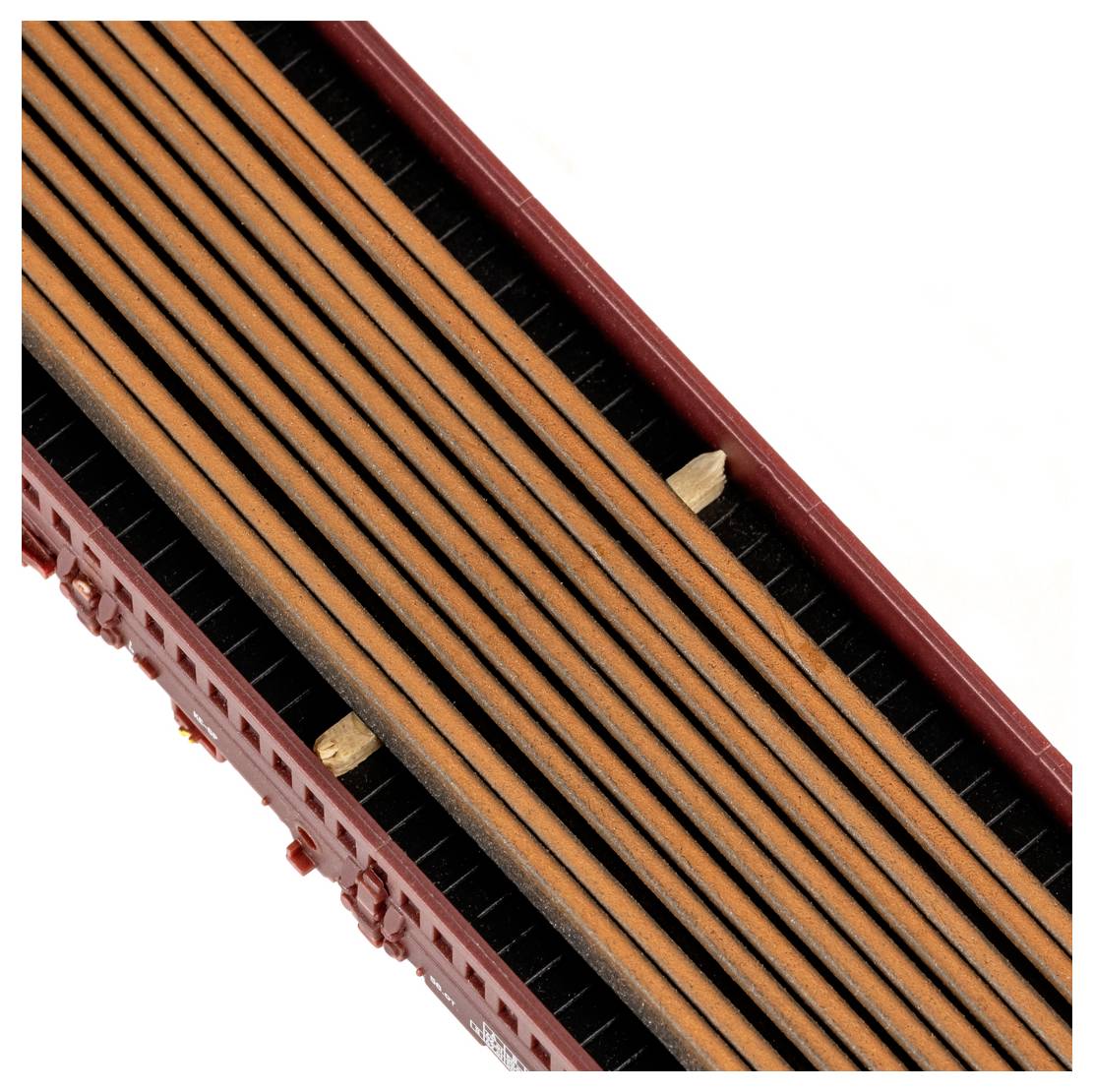 A kép egy vonatkocsit mutat felülnézetből, amely hosszú, egymásra rakott fahasábokat szállít, és két darab fa tömb látható az egymásra rakott rönkök között.