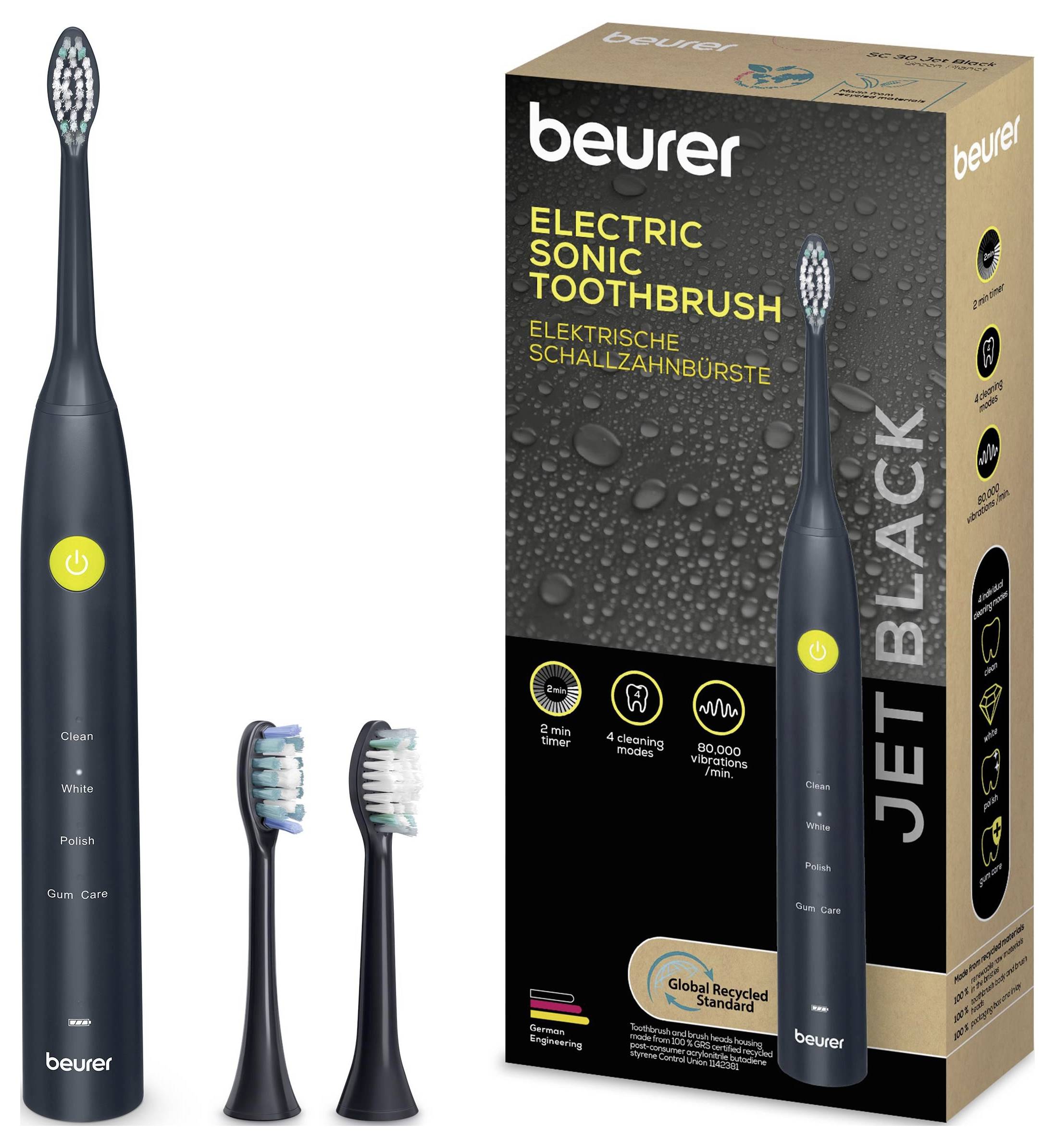 Egy elektromos szónikus fogkefe, két pótfejjel, amelyek mellett a „beurer Jet Black" feliratú csomagolása látható.