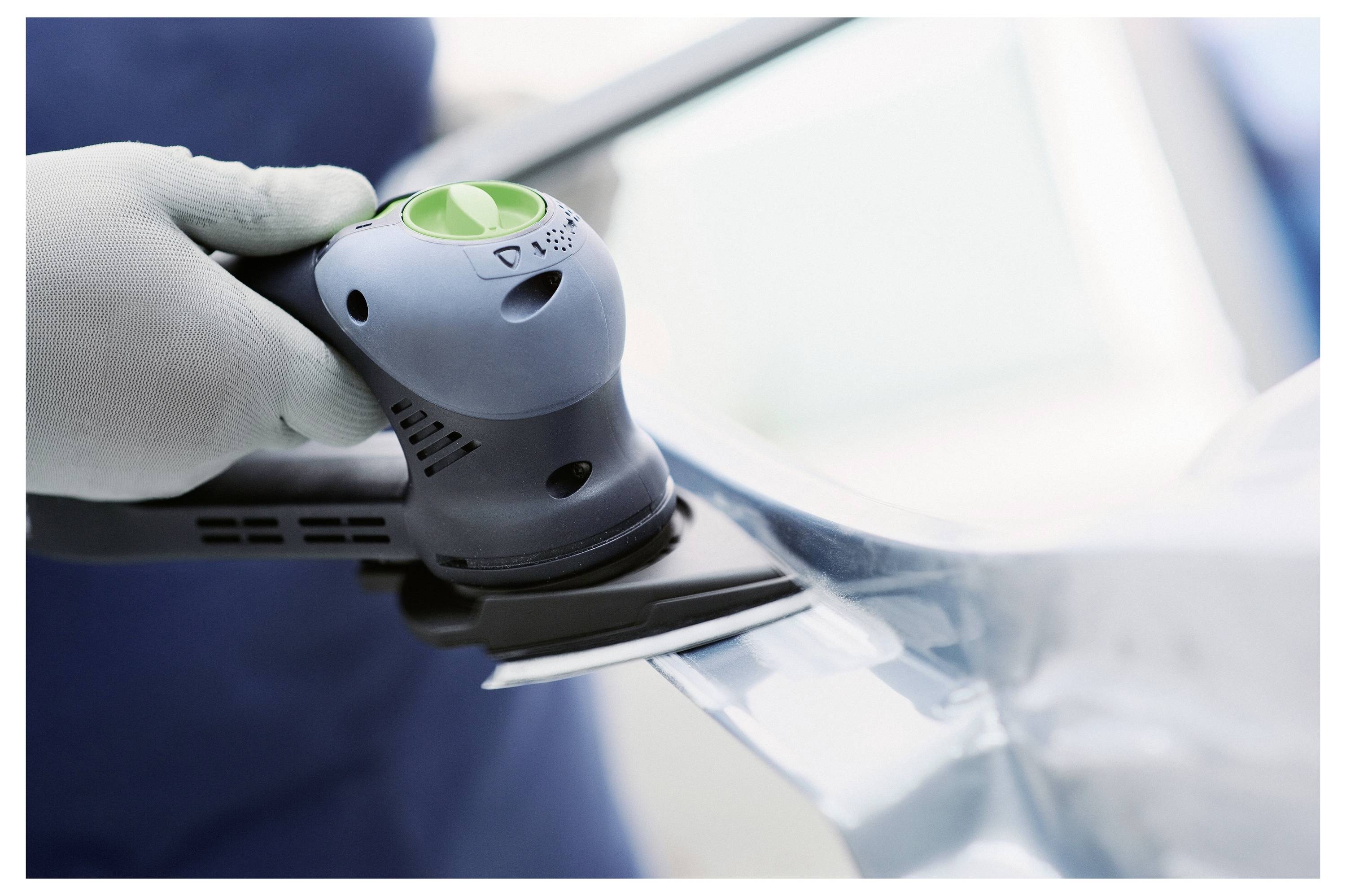 Egy személy egy Festool marógépet használ, hogy egyenes barázdákat vágjon egy fa deszkára, a műhelyi környezetben a pontosságra és az irányíthatóságra összpontosítva.