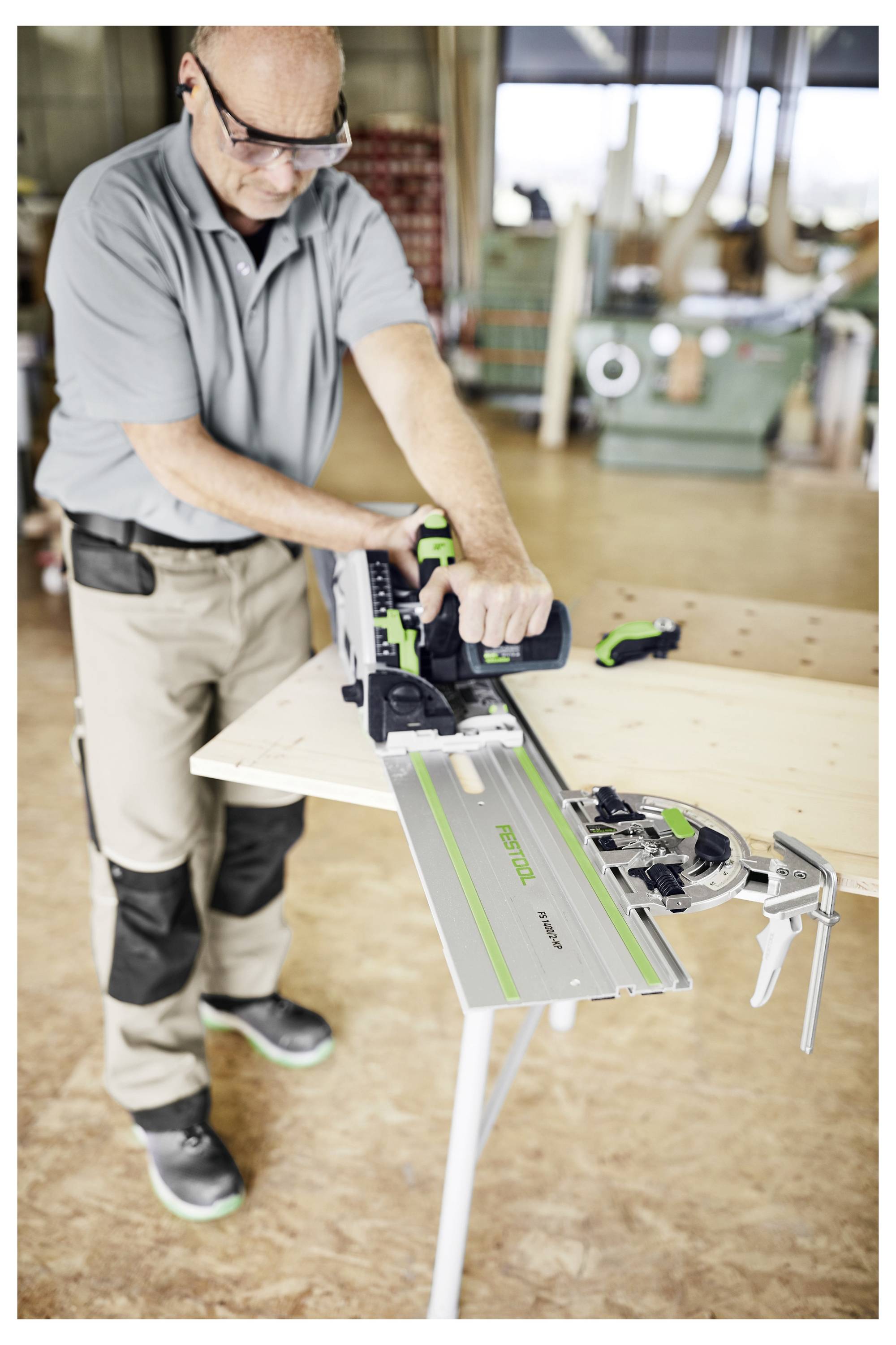 Egy személy elektromos szerszámot használ fa vágásához egy munkapadnál a műhelyben.