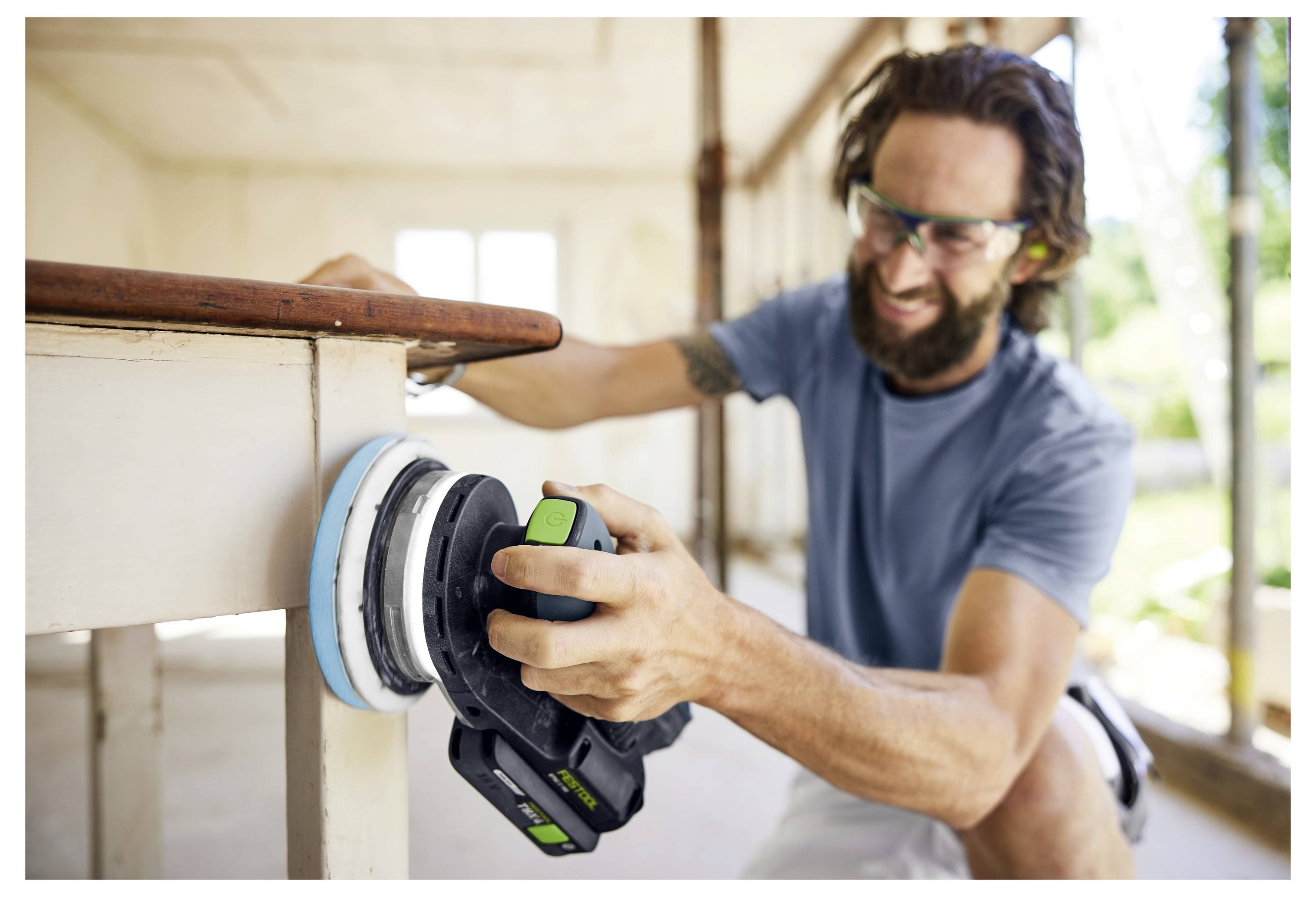 Egy személy kézben tartható elektromos marógéppel egy fadesza szélét vágja, biztosítva a precizitást és a simítást az asztalosmunkában.