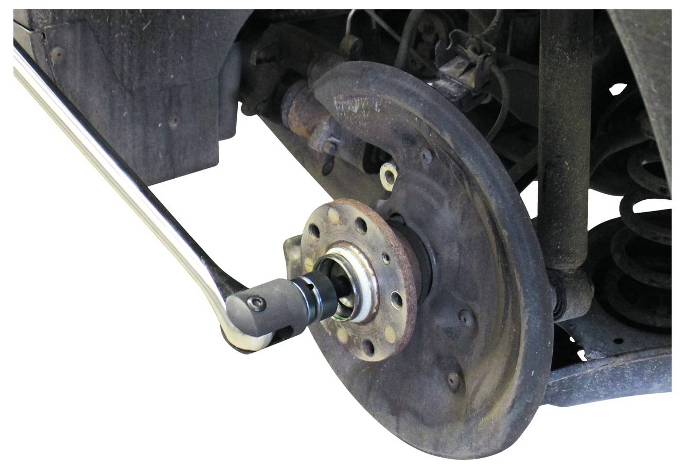 Egy fémmű szerszám egy jármű kerekagyához csatlakozik, gumiabroncsi eltávolítási vagy javítási folyamatot mutatva. A körülvevő terület piszkos és kopott.