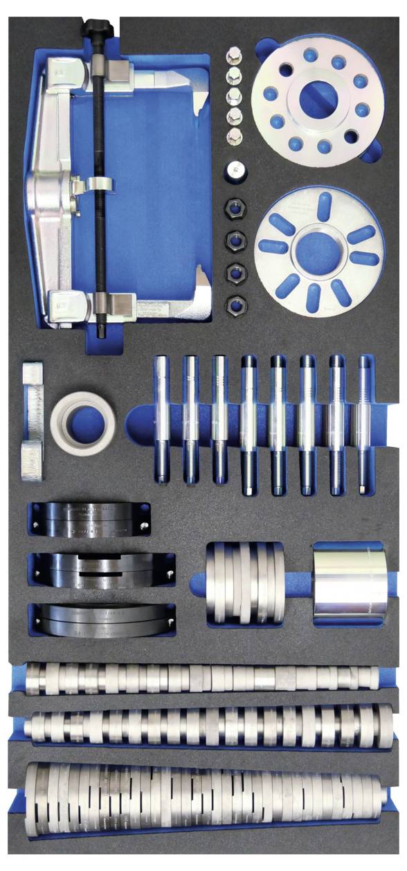 Egy rendezetten szervezett precíziós fémből készült alkatrészek és szerszámok halmaza, habszigetelésű tokba rendezve, amely korongokat, rudakat és kerek alkatrészeket tartalmaz.
