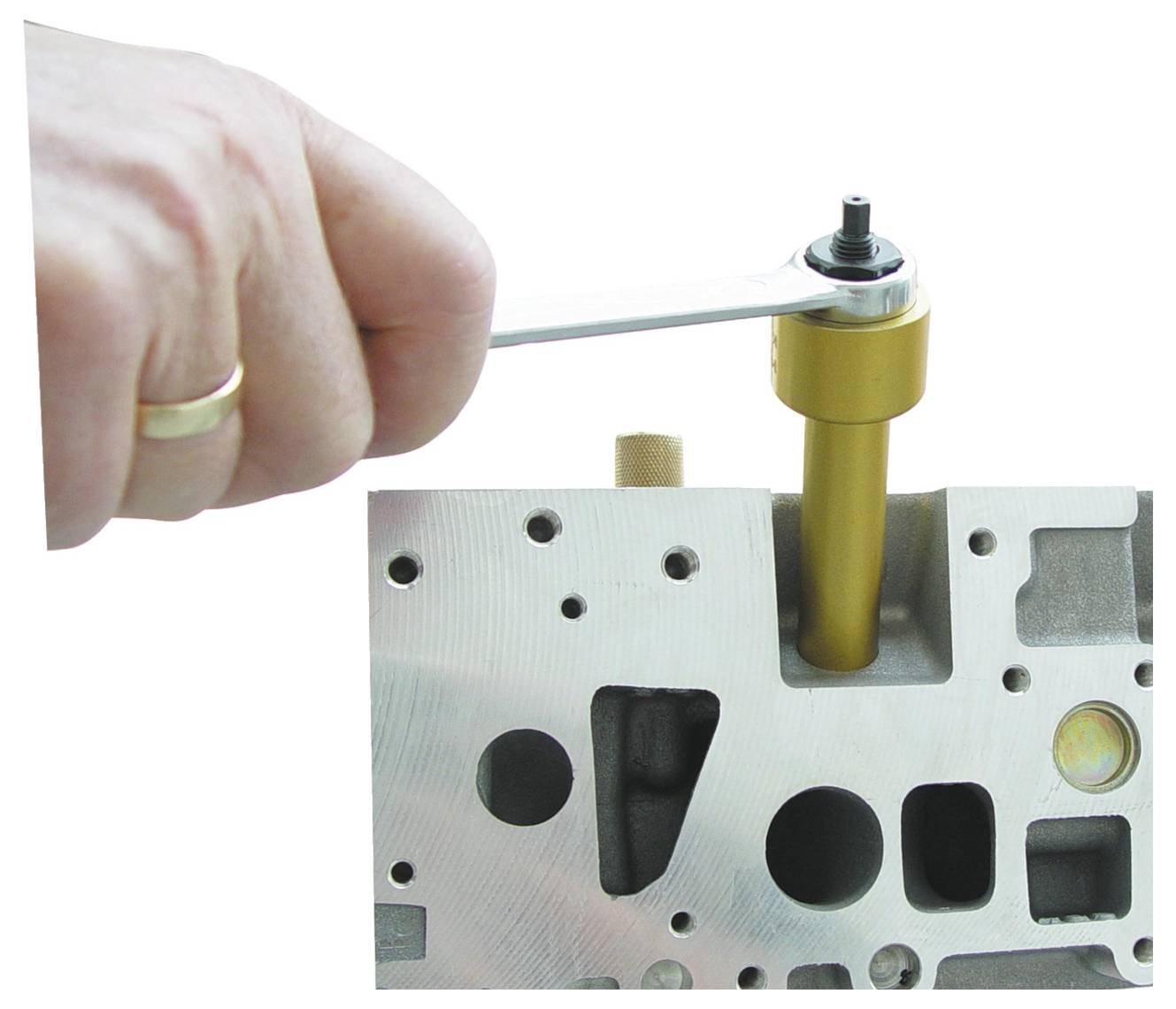 Egy kéz csavarhúzóval állít be egy alkatrészt egy fémes motorblokkon, amely egy karbantartási vagy javítási folyamatot szemléltet.