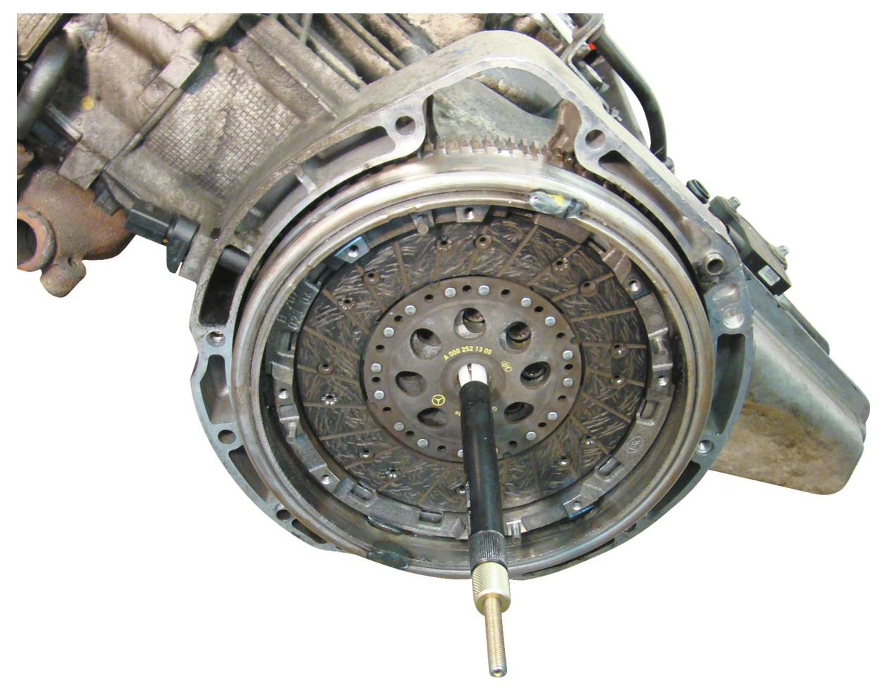 Egy autó kuplung szerkezetének közeli nézete, amely a körkörös nyomólapot és a kuplung tárcsát mutatja egy középpontban lévő igazító szerszámmal.