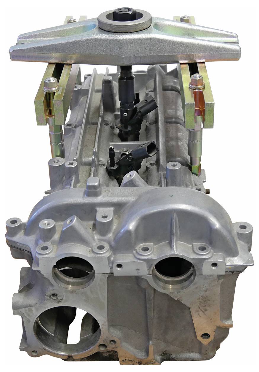 Egy motorblokk egy fölötte elhelyezkedő szerszámmal az igazításhoz vagy javításhoz, mely csavarokat és csatlakozási pontokat mutat.