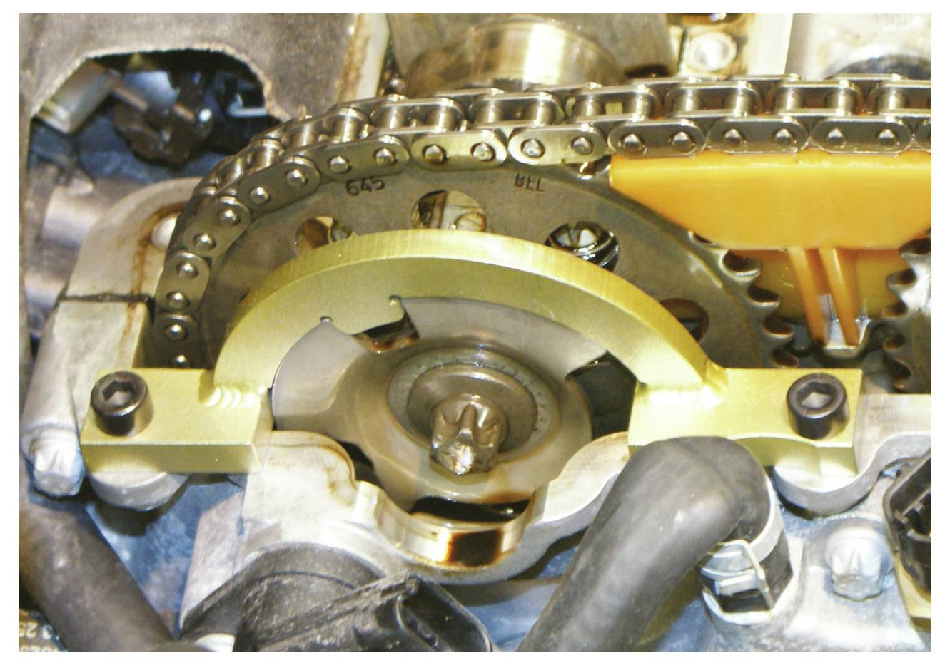 Motor időzítőláncának és fogtűs kerékének mechanizmusa, látható fogaskerekekkel, lánc-feszítővel és fém alkatrészekkel, amely a mechanikai funkciót jelzi.