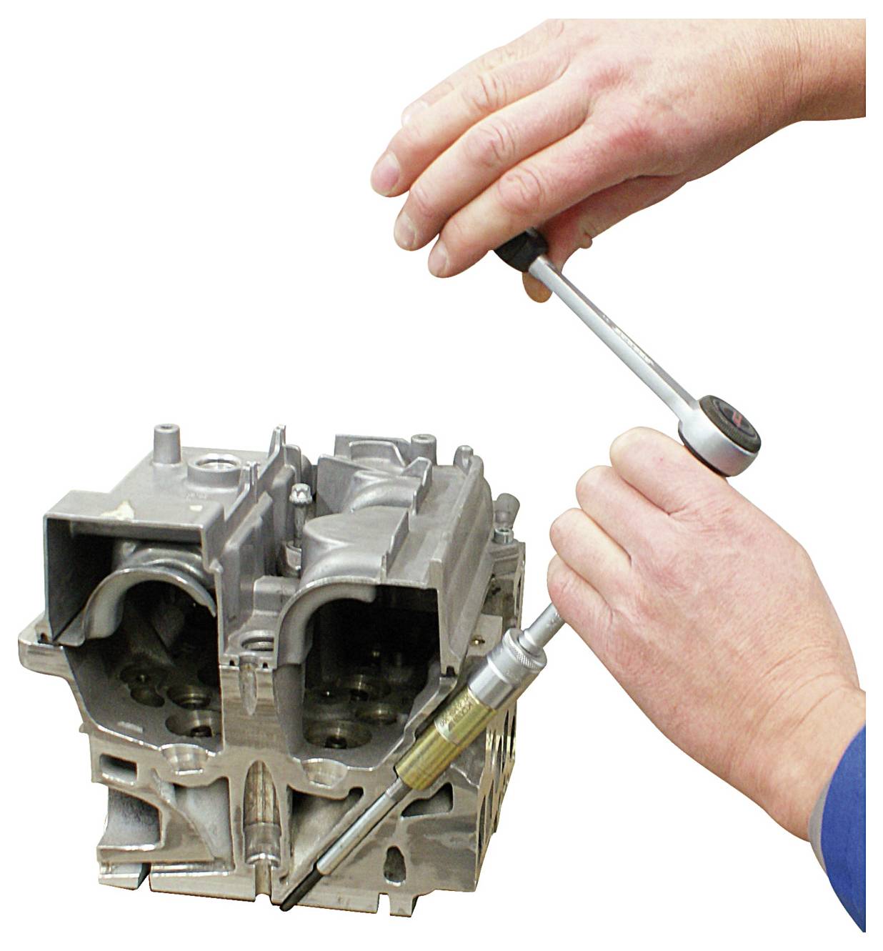 Kezek egy nyomatékkulcs segítségével meghúznak egy csavart egy fémes motorblokkon, ezzel a mechanikai javítást vagy összeszerelést demonstrálva.