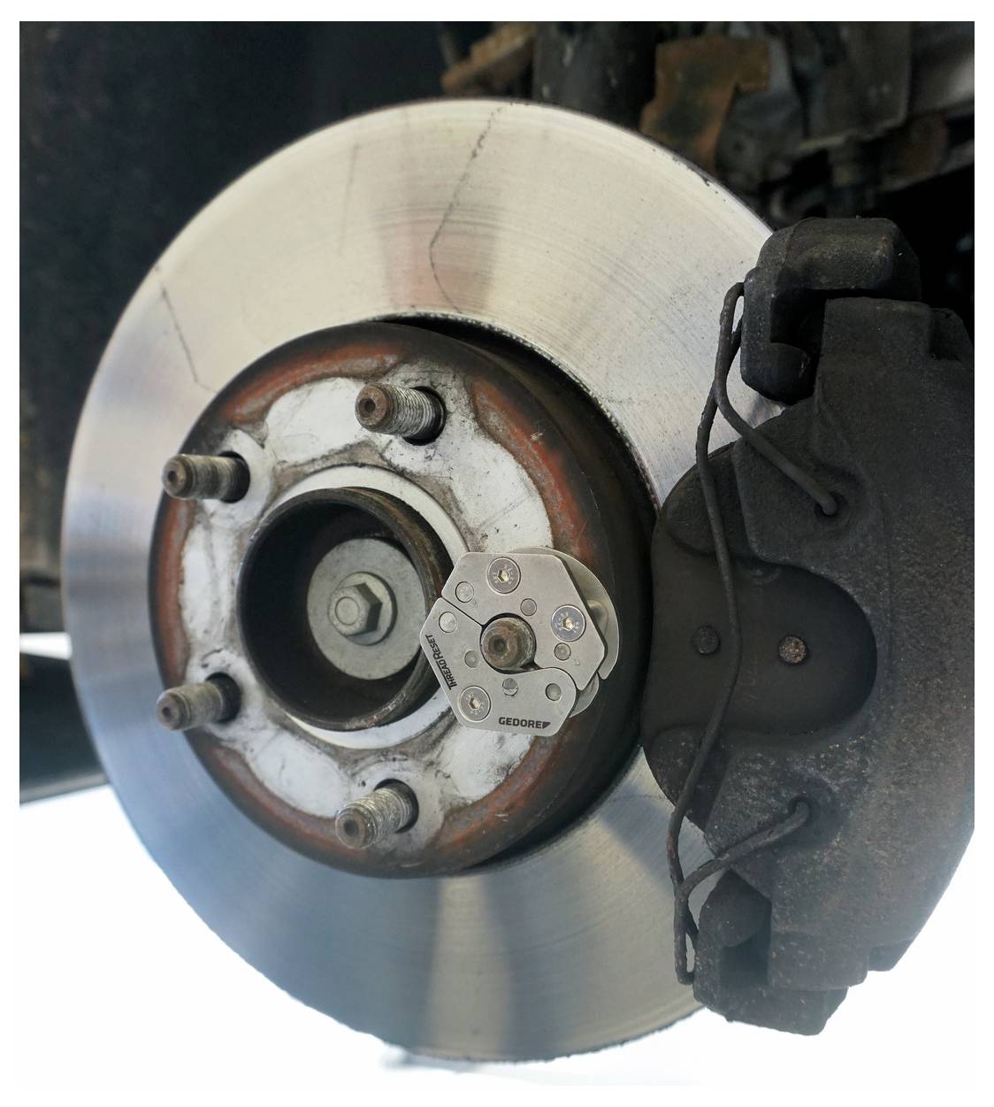 Egy autó tárcsafékszerelésének közeli képe, amely a rotort, a fékkalibert és a szerelési csavarokat mutatja, kiemelve a mechanikai alkatrészeket.
