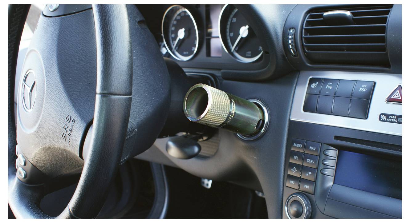 Egy kék autóbeltéri levehető eszköz segítségével egy kéz egy autó panelcsipeszt távolít el egy szürke panelről.