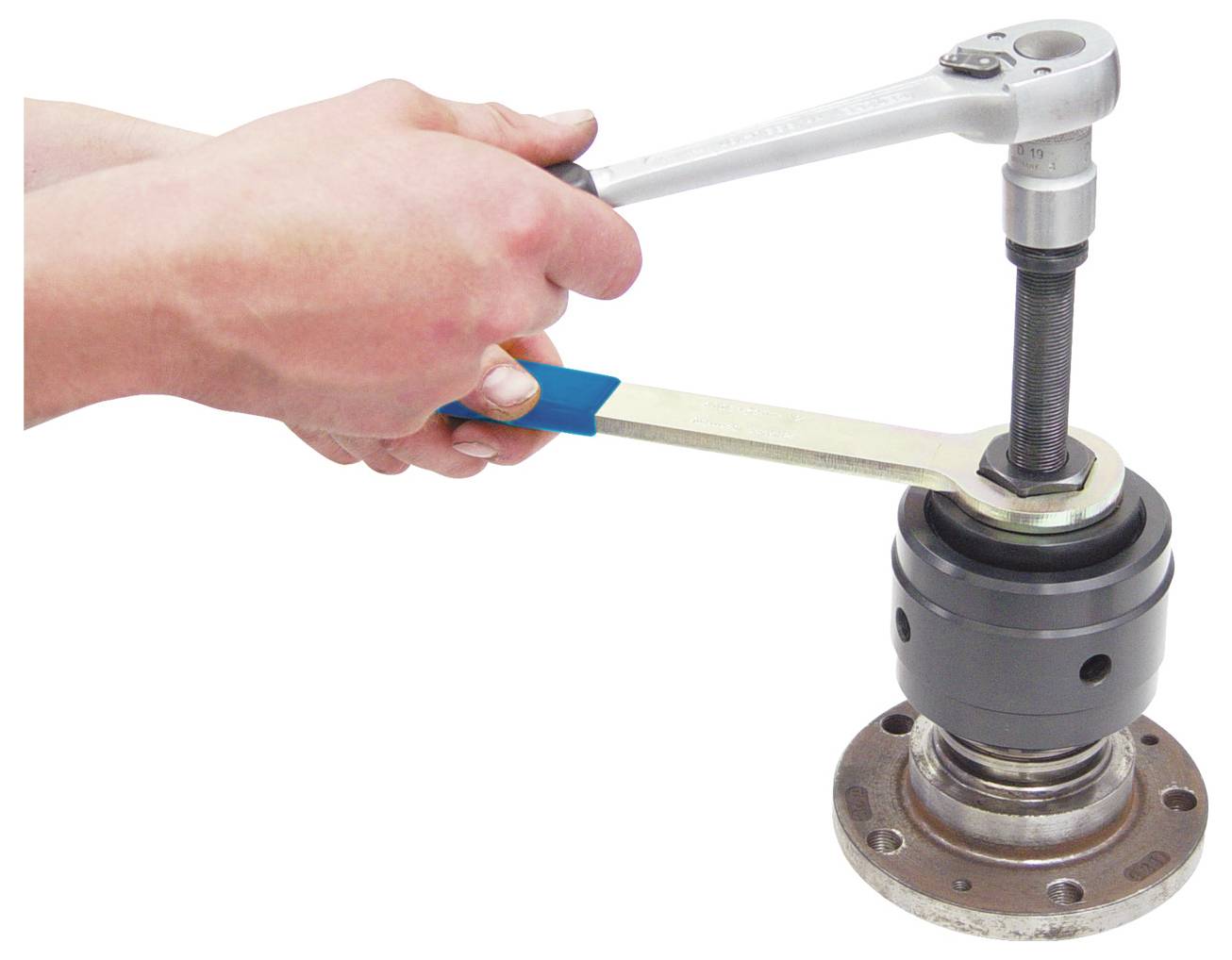 Két kéz csavarkulccsal és csavarhúzóval egy mechanikai alkatrész csavarját szorítja meg.