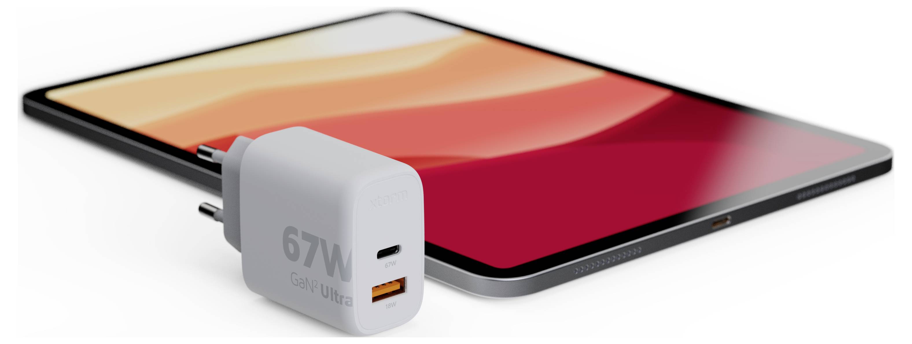 „Egy élénk piros és narancssárga képernyőjű tablet egy 67W-os, két porttal rendelkező USB töltővel együtt van kiállítva, amely a töltési képességet mutatja be."
