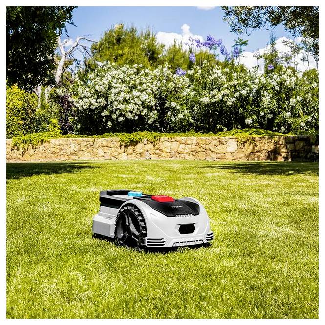 Egy robotfűnyírógép autonóm módon nyírja a gondosan nyírt pázsit egy napos kertben, fákat és egy kőfalat körülvevő területen.