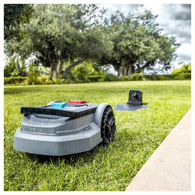 Egy robotikus fűnyíró átkelel egy füves udvaron könnyű esőben, üde fák láthatóak a háttérben, kiemelve az automatizált fűnyírást.