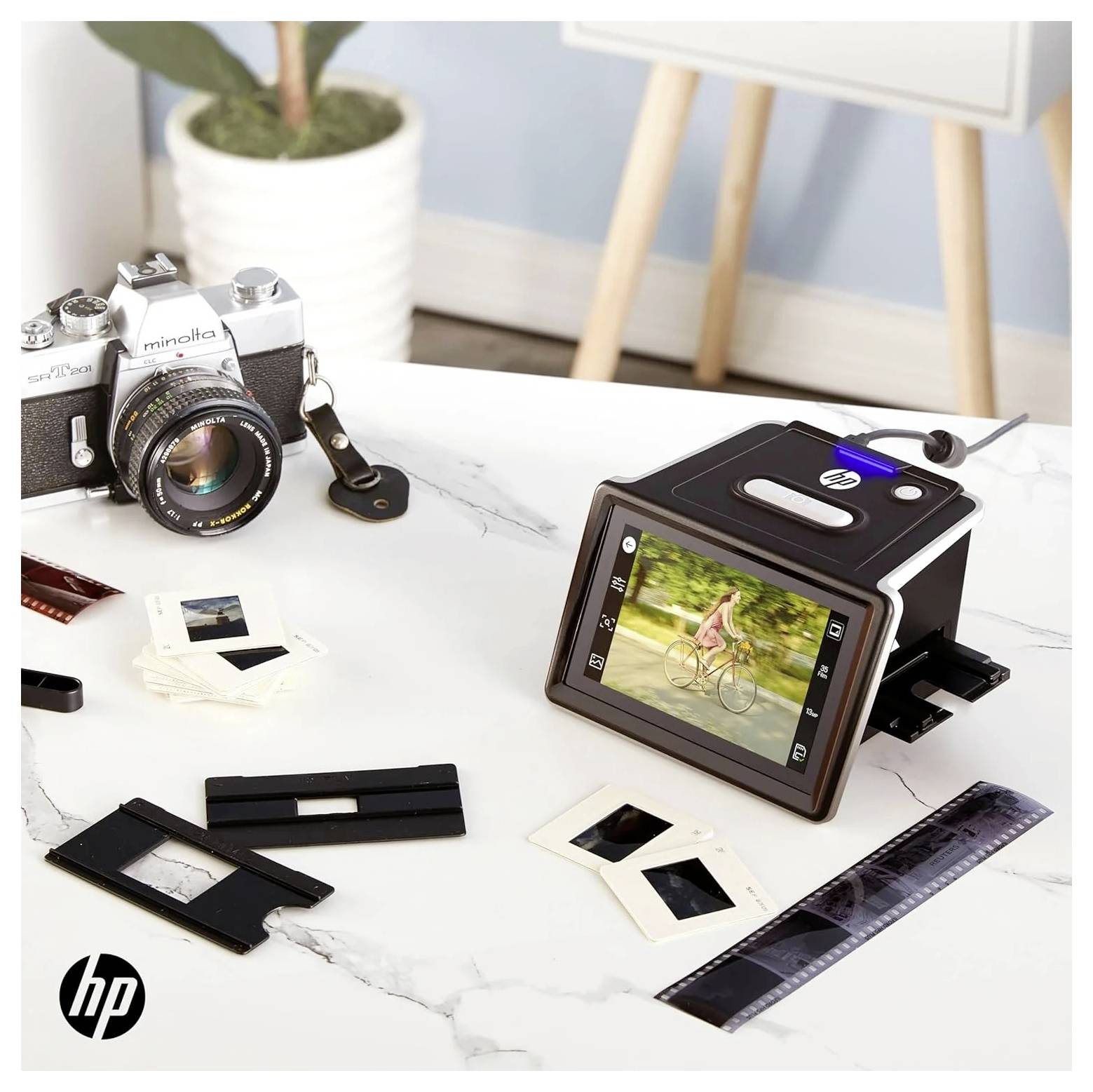 Egy modern diapozitív-szkenner látható, amely régi filmdiákat digitális képekké alakít át, míg az asztal mellett egy analóg kamera van kihelyezve.