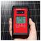 'Egy kéz egy digitális napenergia-intenzitás mérőt tart, amely 789 W/m², 16°C és 349° értékeket mutat. A háttérben napenergia panelok láthatók.'