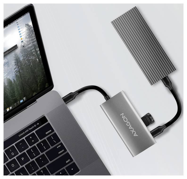 Laptop ezüst Axxion dokkolóhoz csatlakoztatva kábelek segítségével, csatlakoztatott táblagéppel és külső meghajtóval, fehér felületen látható.