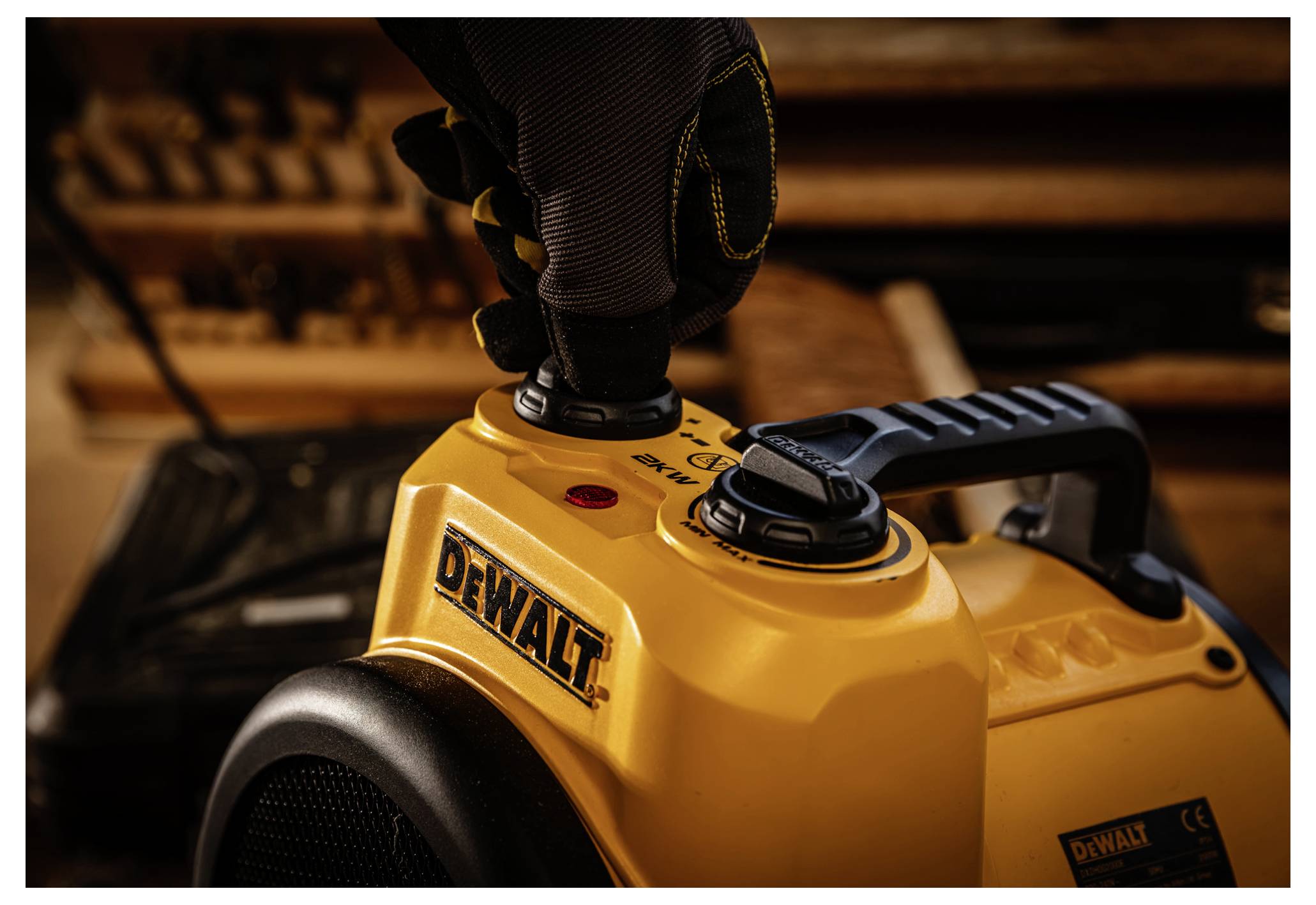 Egy sárga DEWALT elektromos szerszám közelképe, kezeszsákó viselő kéz a tetején lévő szabályozógombot állítja be.