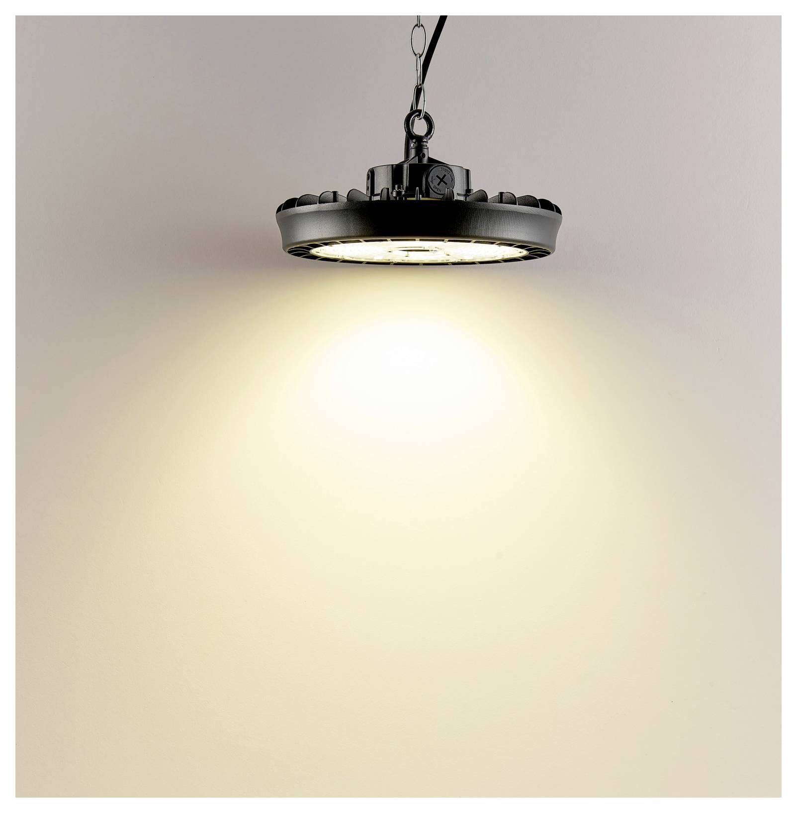 Mennyezetre szerelt ipari LED-es lámpatest, amely meleg, erős fénysugarat vet egy sima falra.