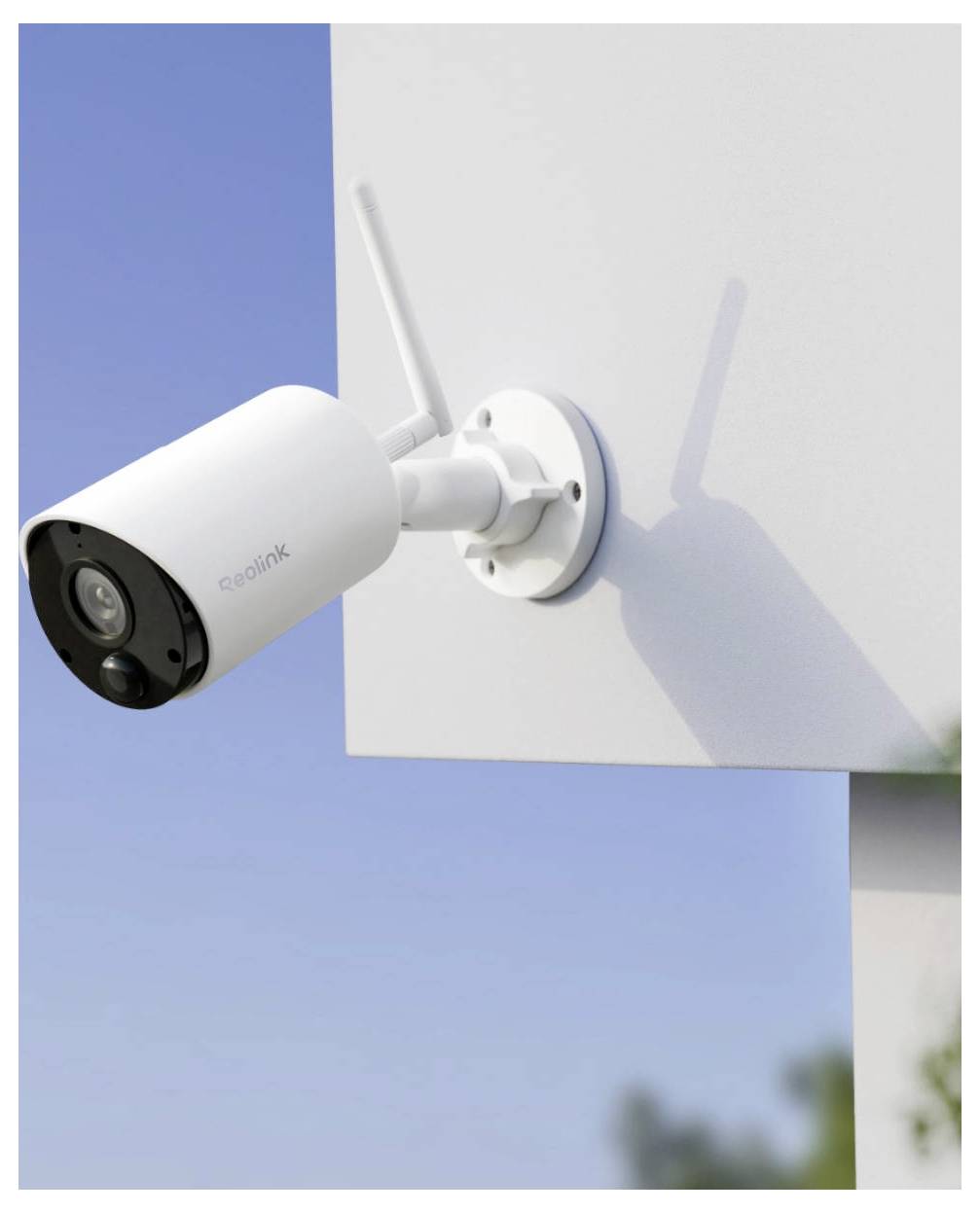 Fehér vezeték nélküli biztonsági kamera egy épület falára szerelve, kifelé szögezve a kék ég ellen