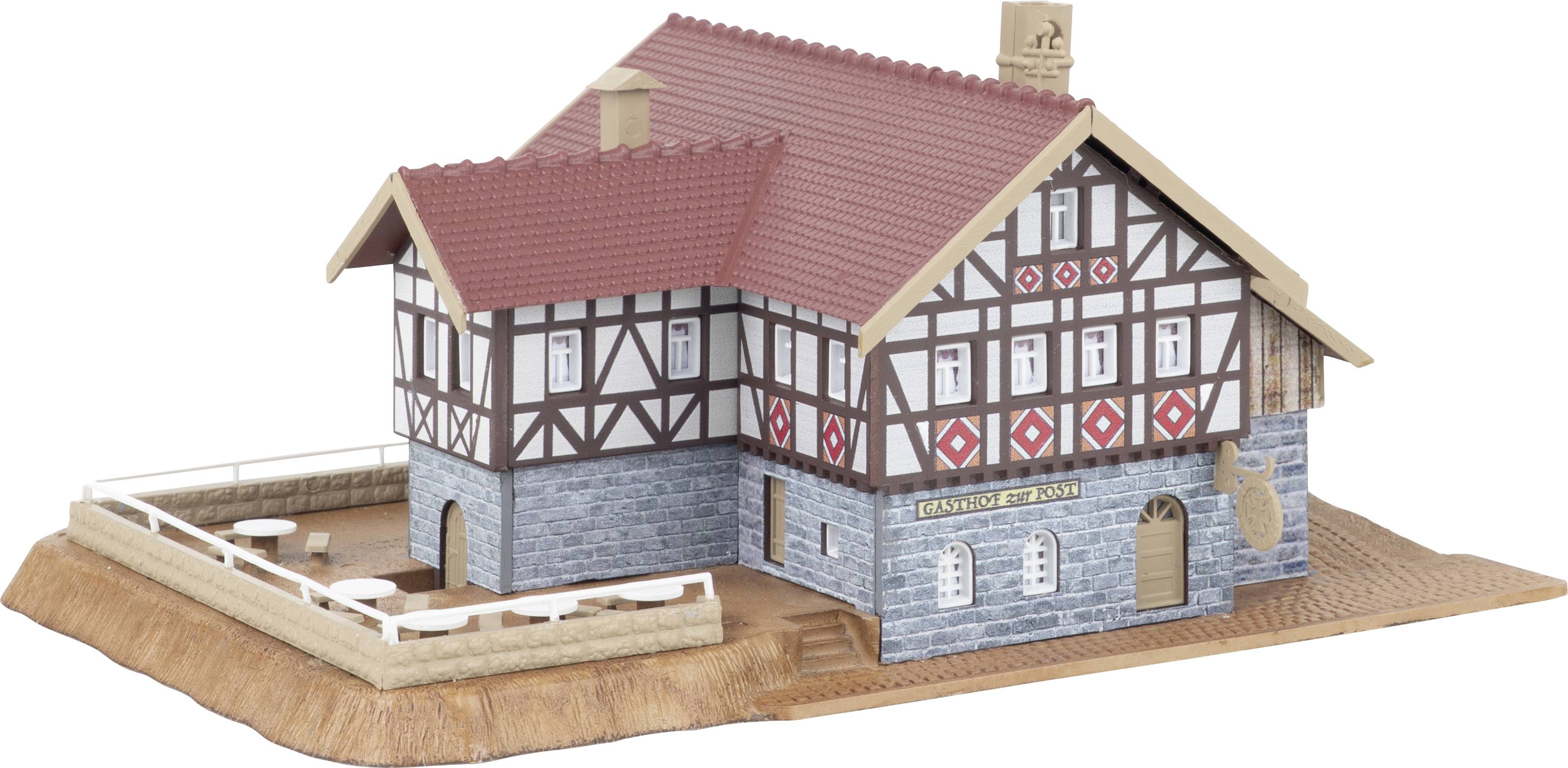 Félvályogházas modell piros tetővel és kőalapozással, kiállítási platformon bemutatva.