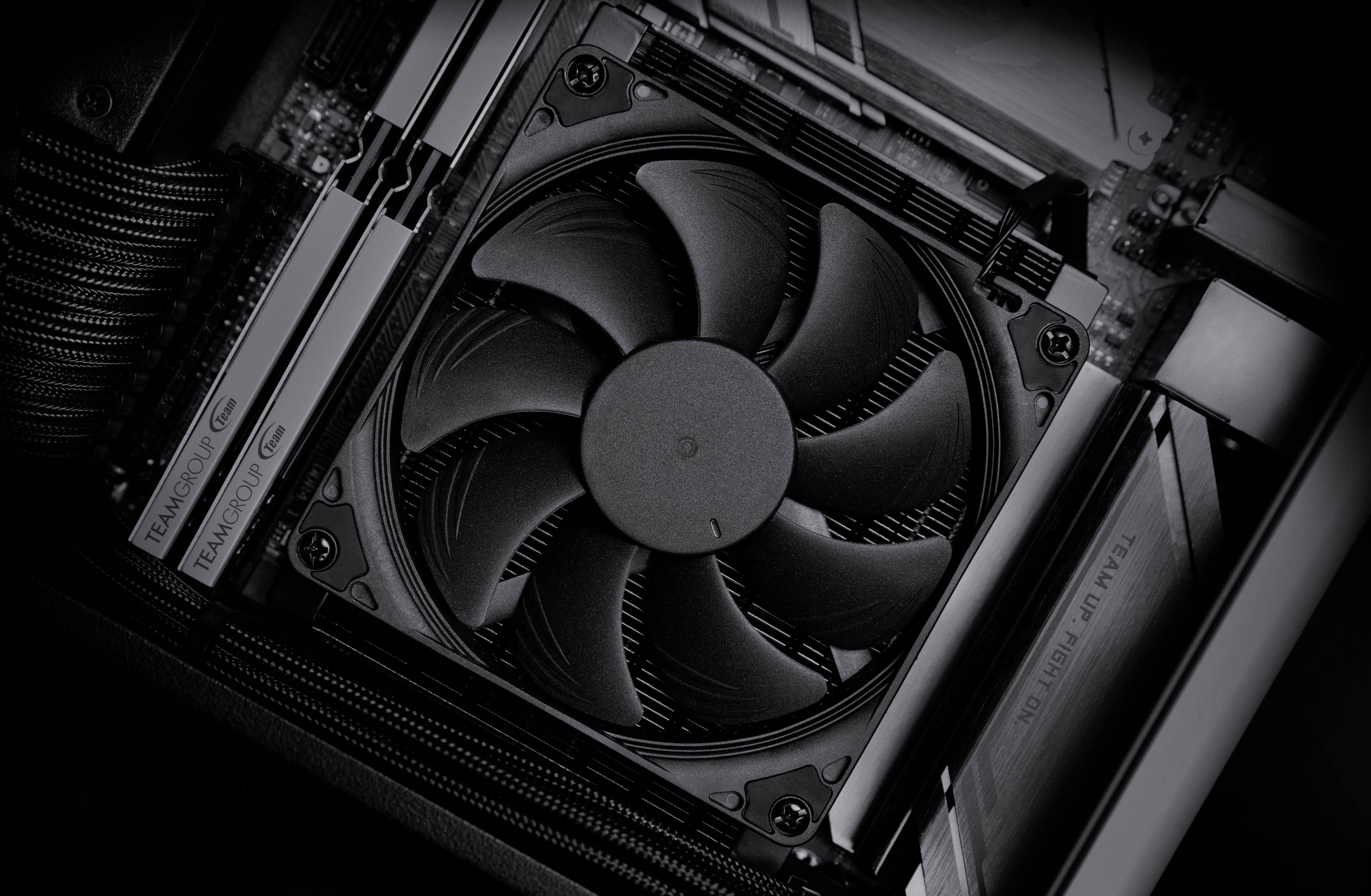 Számítógépes alaplap közeli képe egy nagy fekete hűtőventilátor és memóriamodulok láthatók, amely a ház belsejében lévő PC hardvert mutatja.