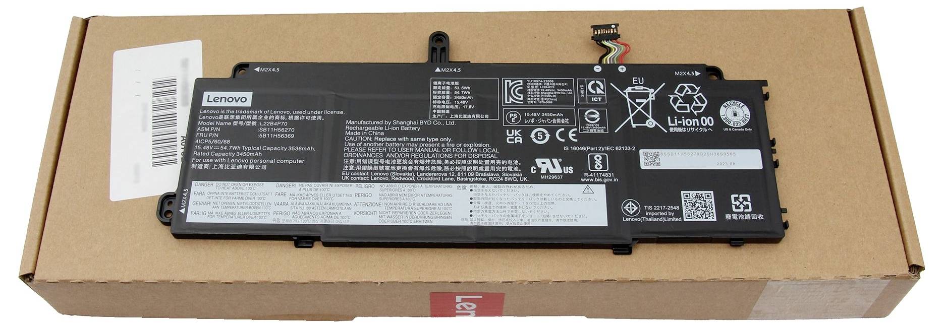 Lenovo laptop akku egy kartondobozon pihenve, látható címkével és biztonsági szimbólumokkal.