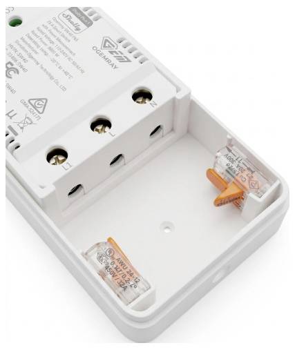 Nyitott fehér elektromos eszköz burkolat, amelyen belül jelölt csatlakozási pontok és két kis narancssárga-átlátszó biztosítékgömb-tartó látható.