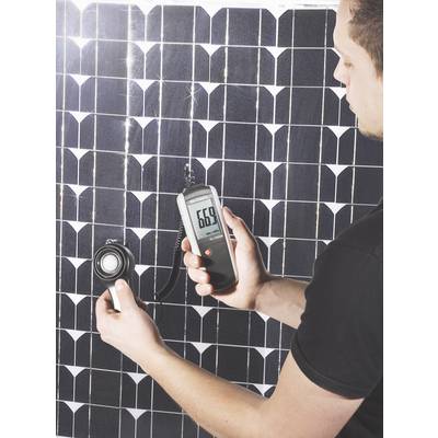 Egy férfi egy digitális mérőkészülékkel méri egy napelemmodul teljesítményét, amely '669'-et mutat.